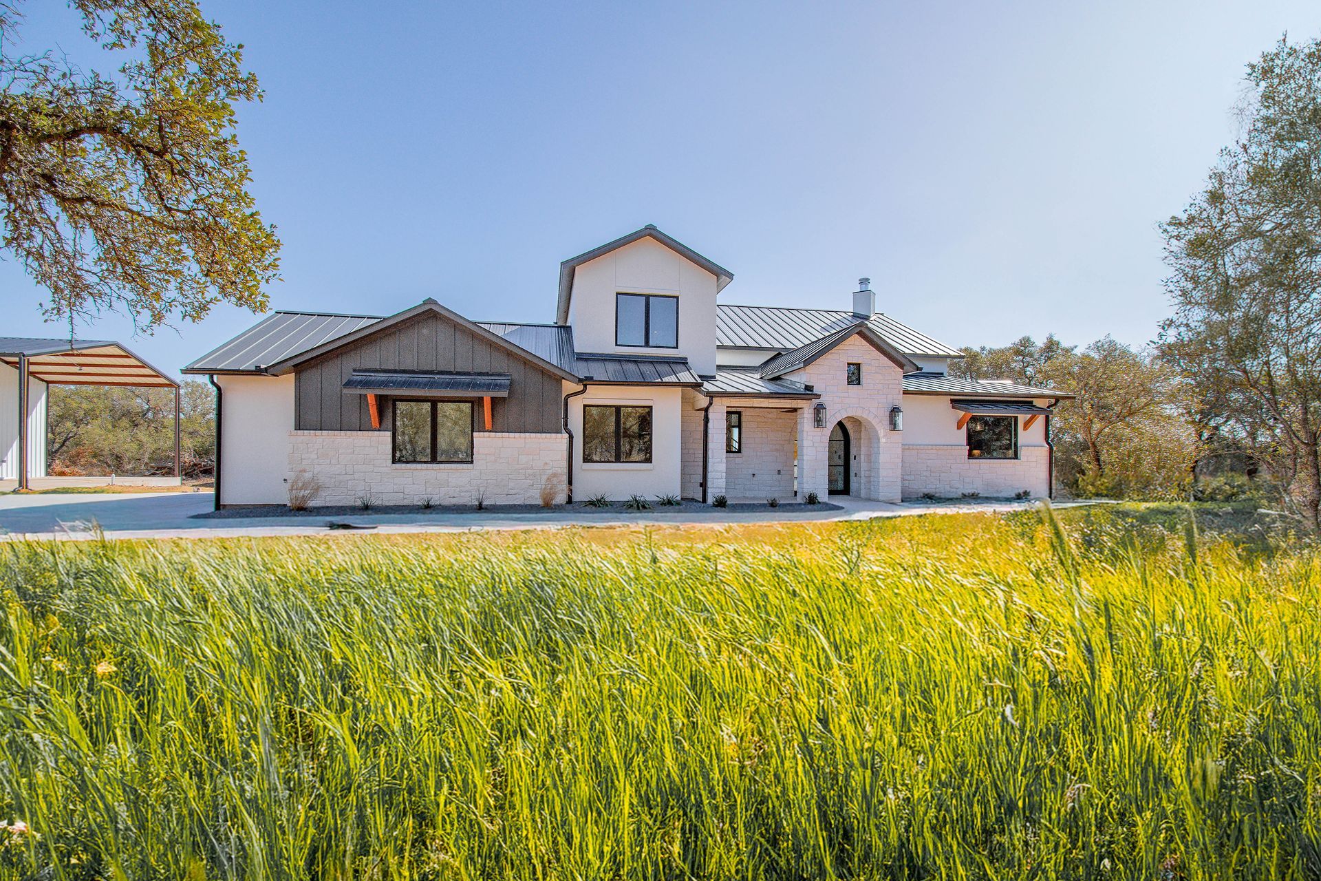 A large white house is sitting in the middle of a grassy field.