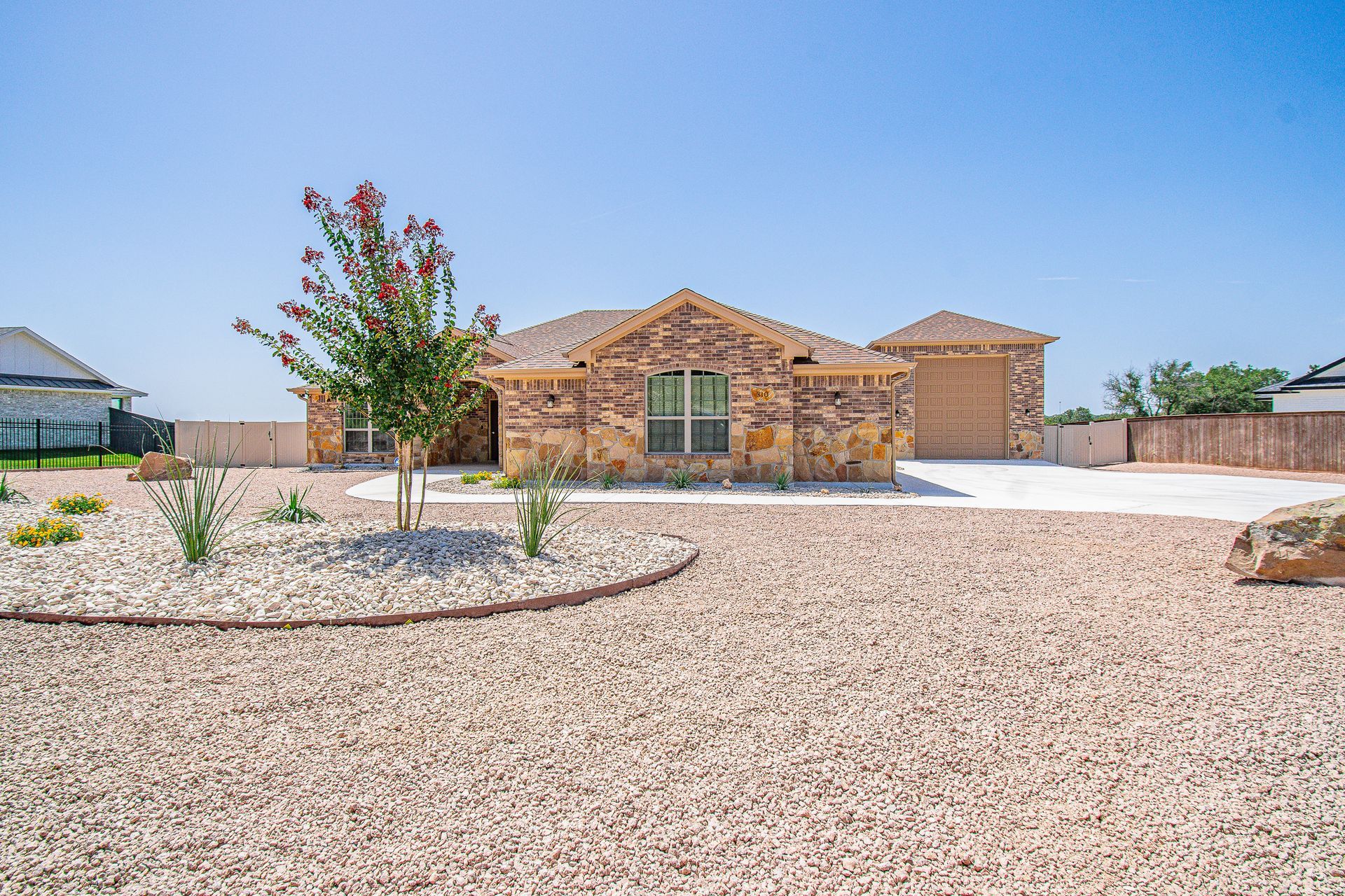 A house with a gravel driveway and a tree in front of it.