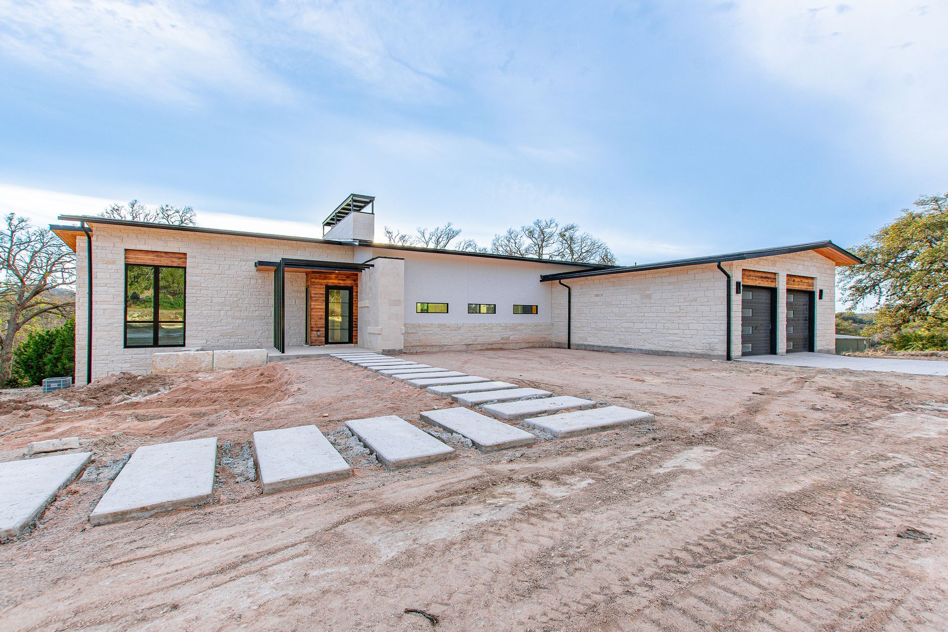 A large white house is sitting in the middle of a dirt field.