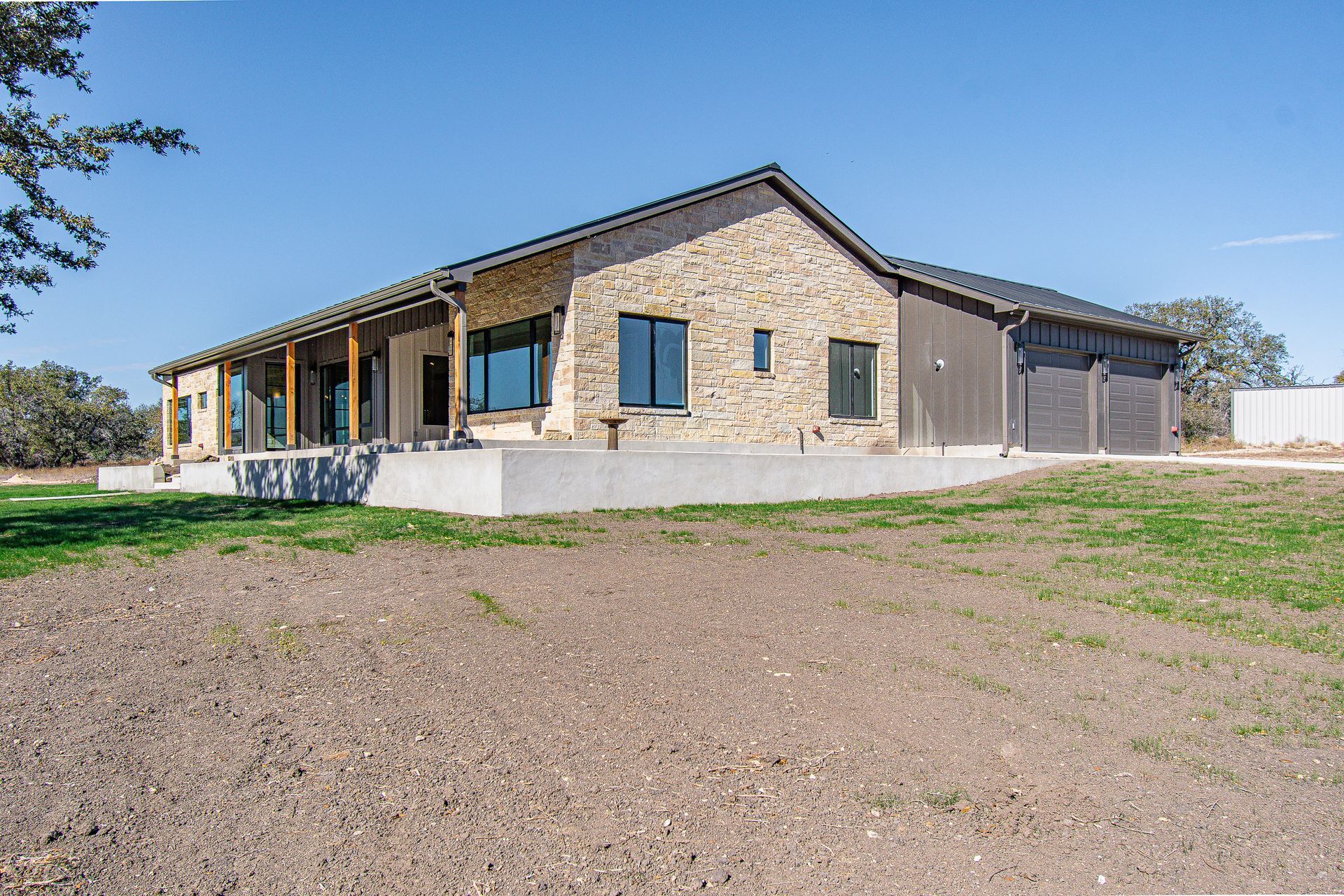 A large house with a lot of windows is sitting on top of a dirt field.