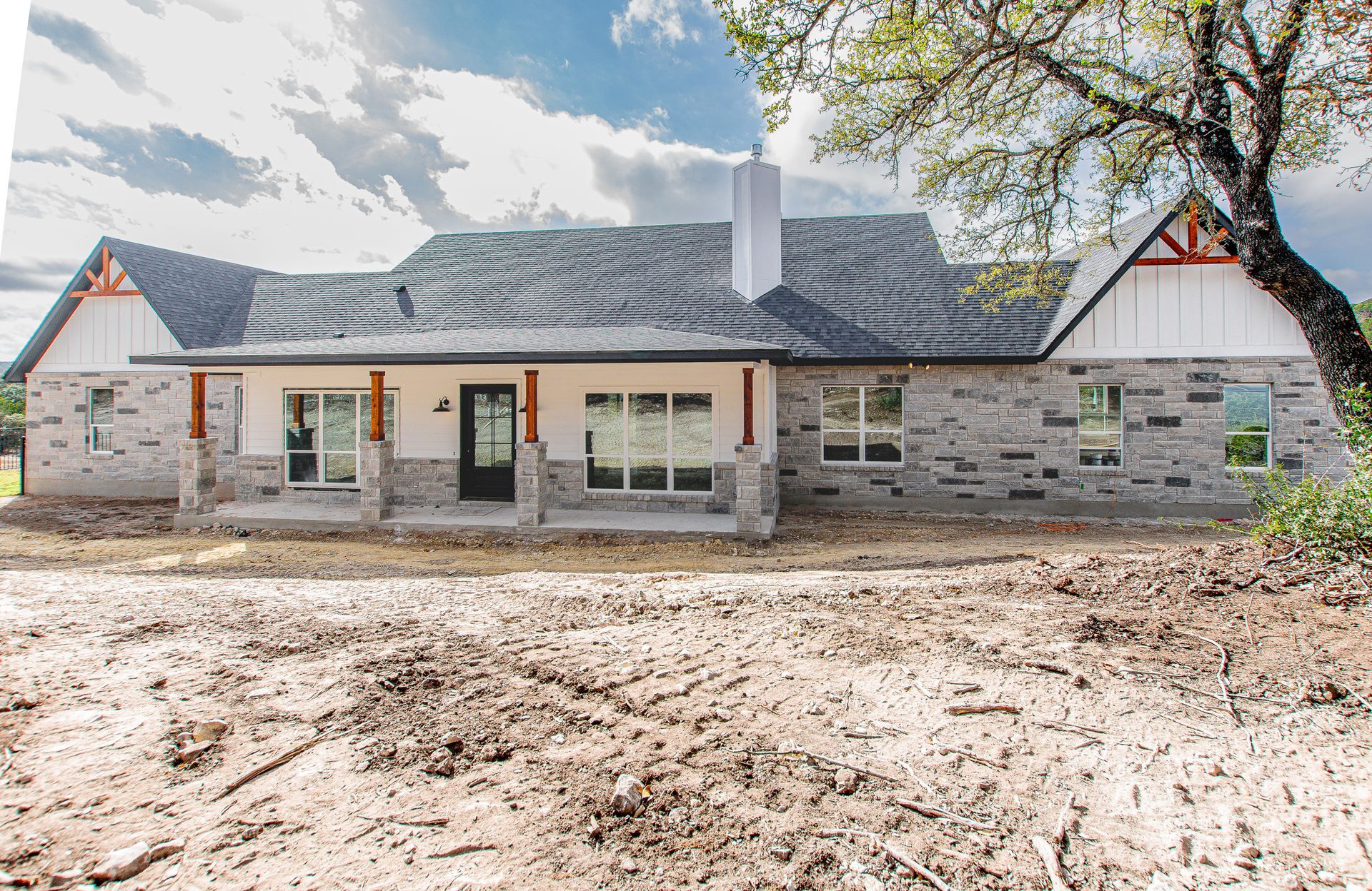 A large brick house is sitting in the middle of a dirt field.