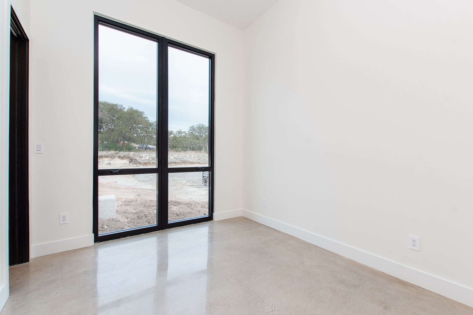 An empty room with two large windows and a sliding glass door.
