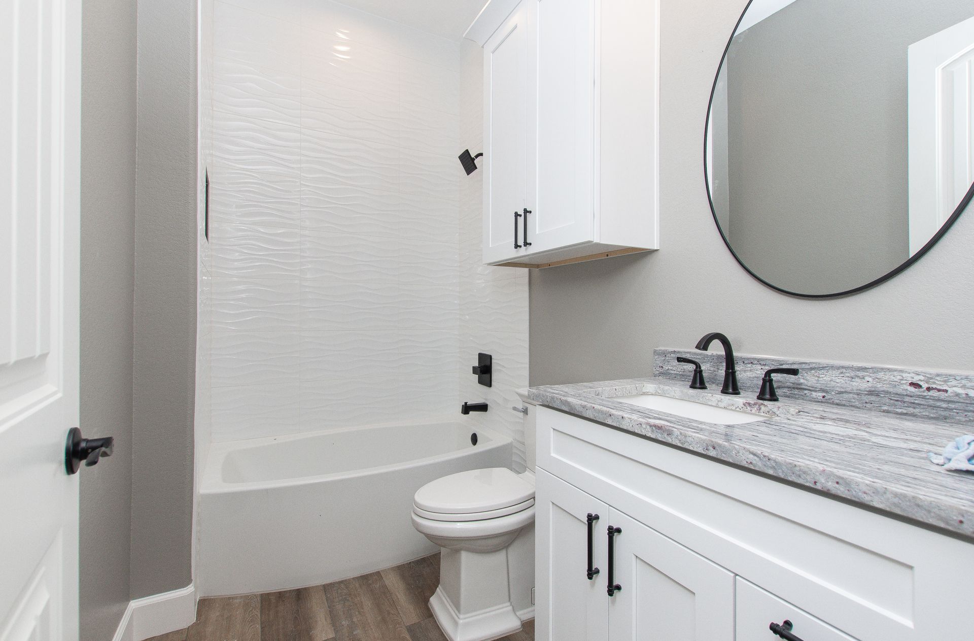 A bathroom with a tub , toilet , sink and mirror.