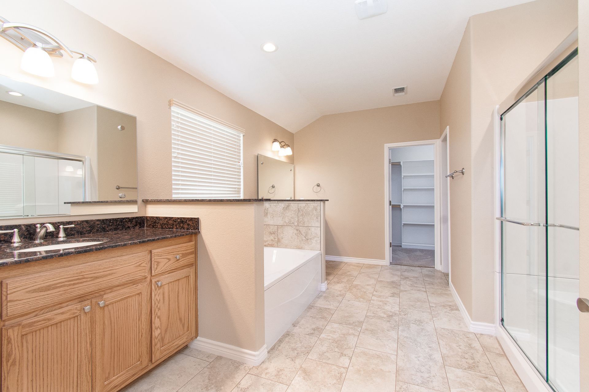 A bathroom with a tub , sink , mirror and walk in closet.