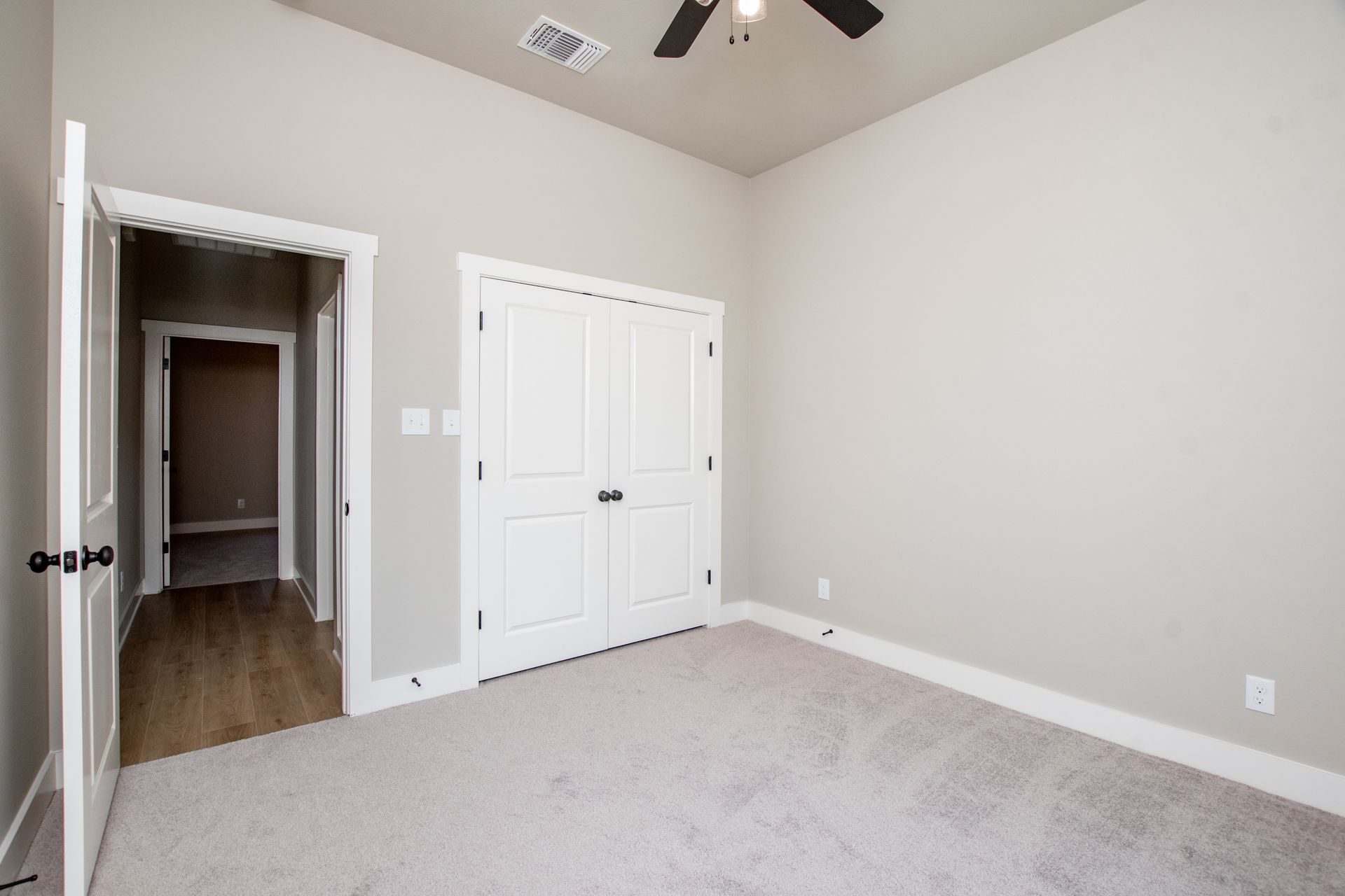 An empty bedroom with a ceiling fan and a large closet.