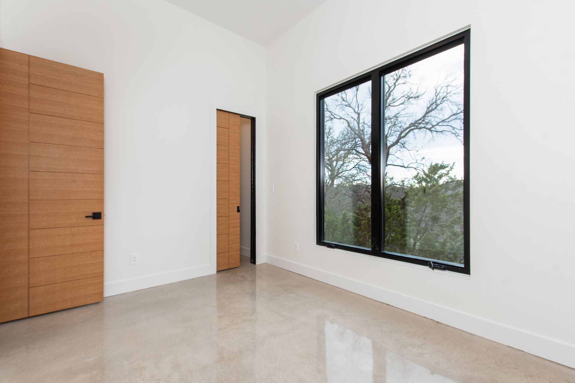 An empty room with two windows and a wooden door.