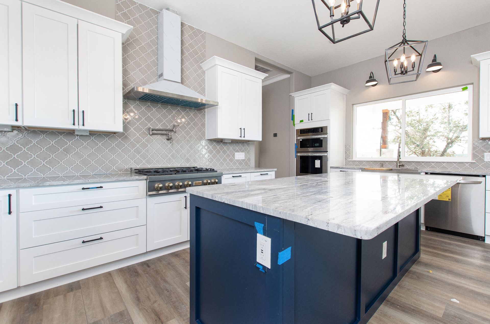 A kitchen with white cabinets and a blue island.