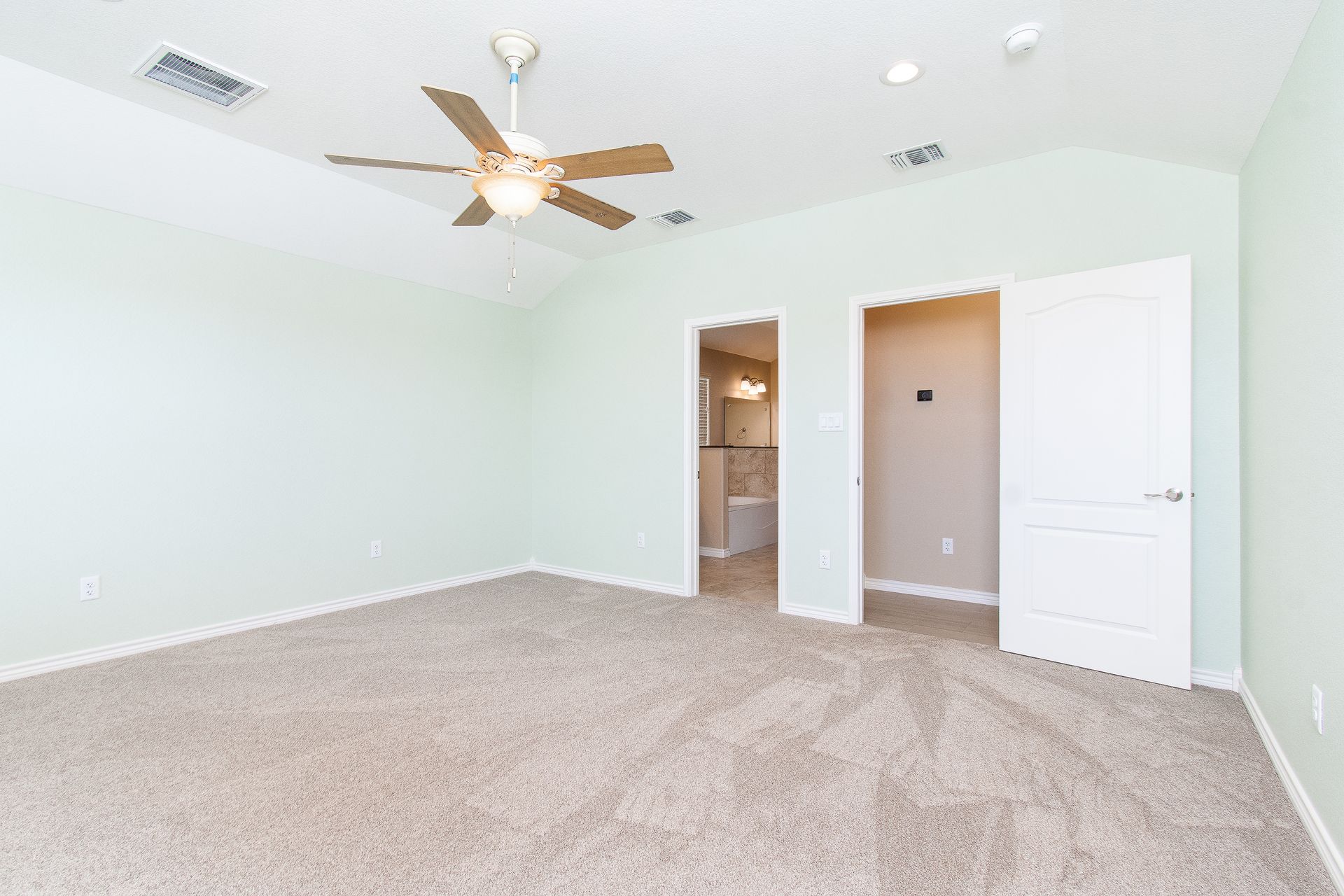 An empty bedroom with a ceiling fan and a closet.