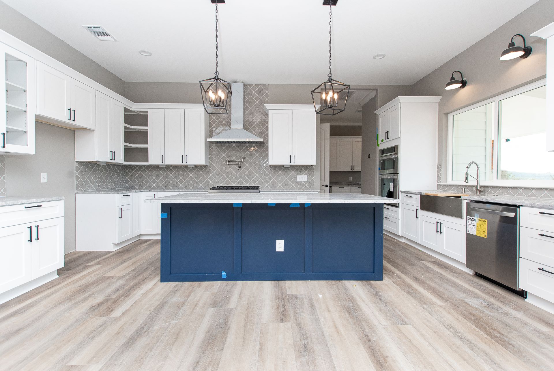 A kitchen with white cabinets and a blue island in the middle.