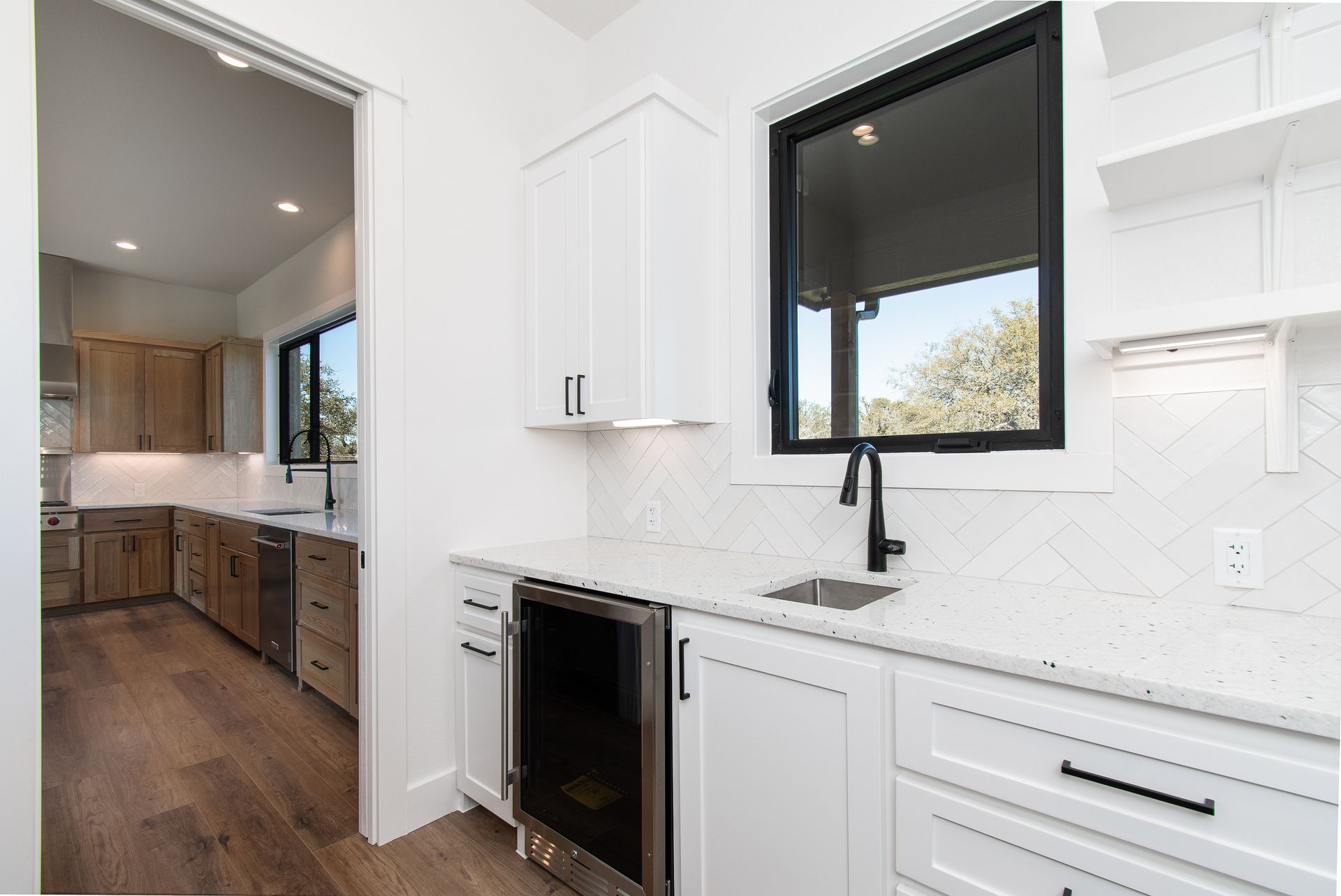 A kitchen with white cabinets , a sink , and a window.