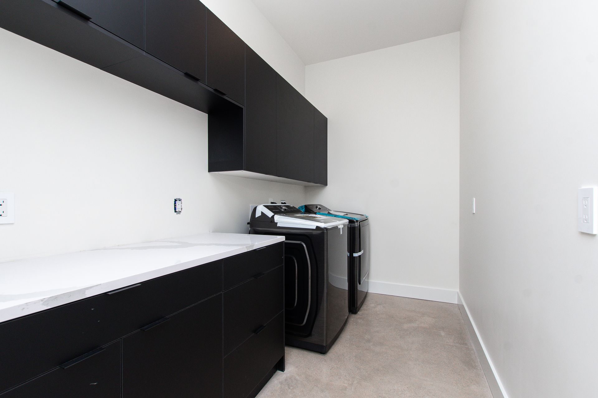 A laundry room with black cabinets and a washer and dryer