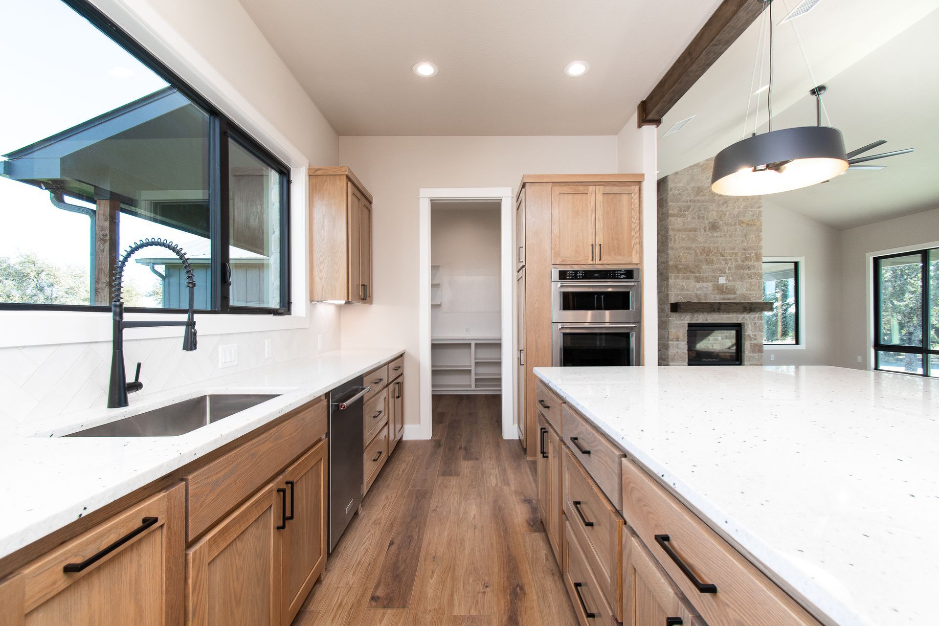 A kitchen with wooden cabinets , white counter tops , and stainless steel appliances.