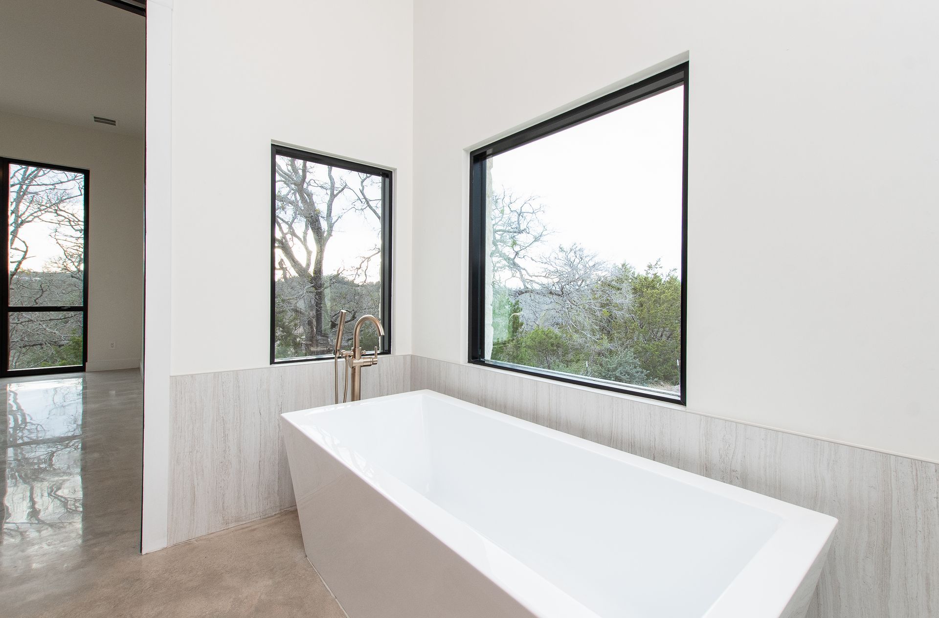 A bathroom with a bathtub and two windows.