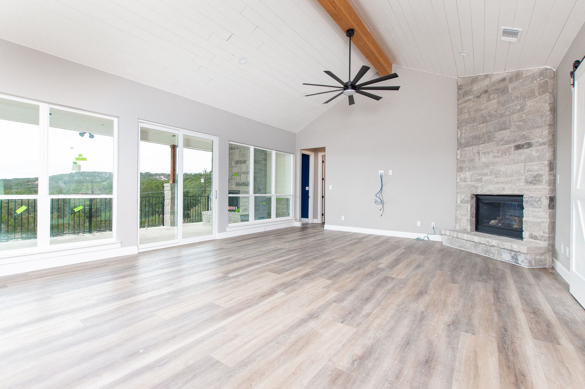 An empty living room with hardwood floors , a fireplace and a ceiling fan.
