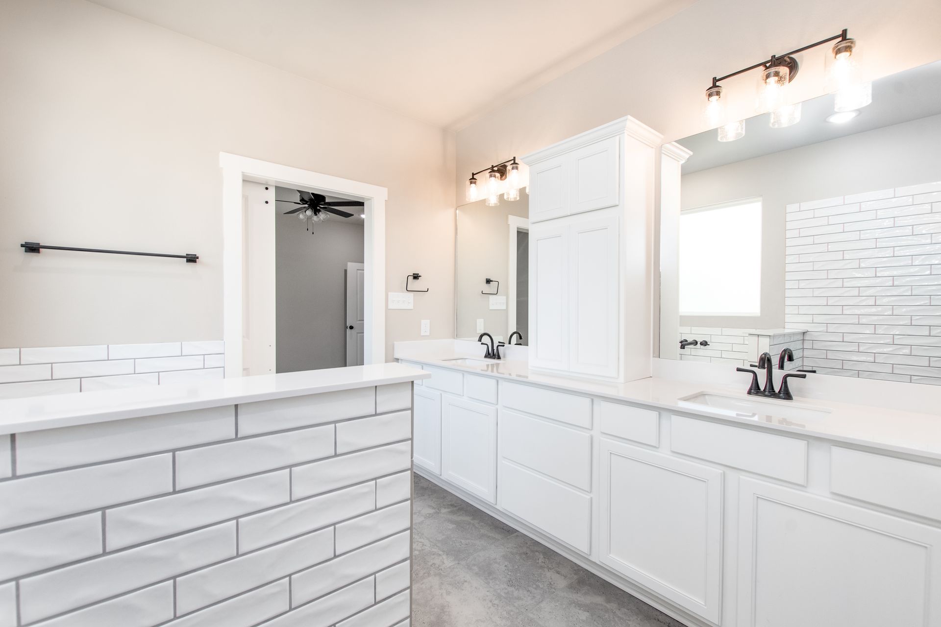 A bathroom with white cabinets and a large mirror.
