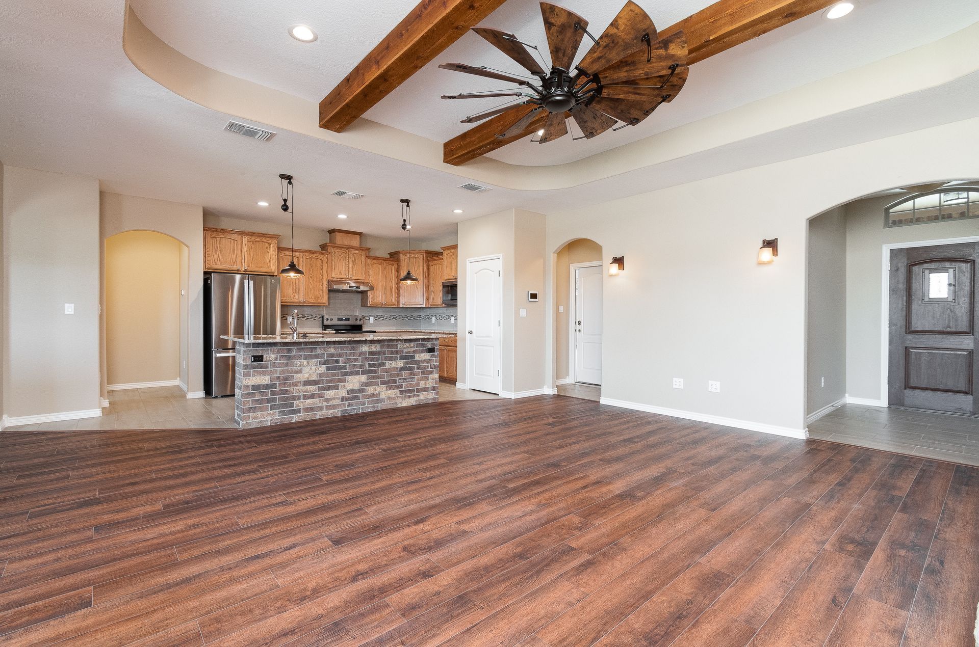 A living room with hardwood floors and a ceiling fan in a house.