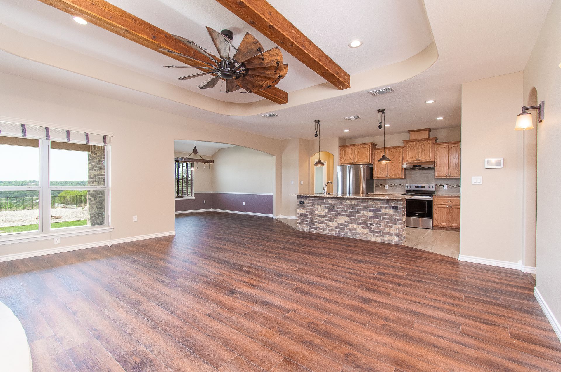 There is a ceiling fan in the living room and a kitchen in the background.