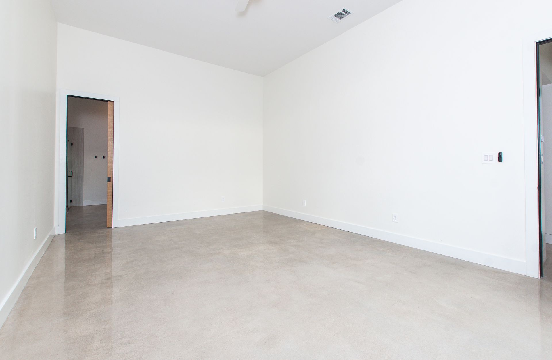 A large empty room with white walls and a marble floor.