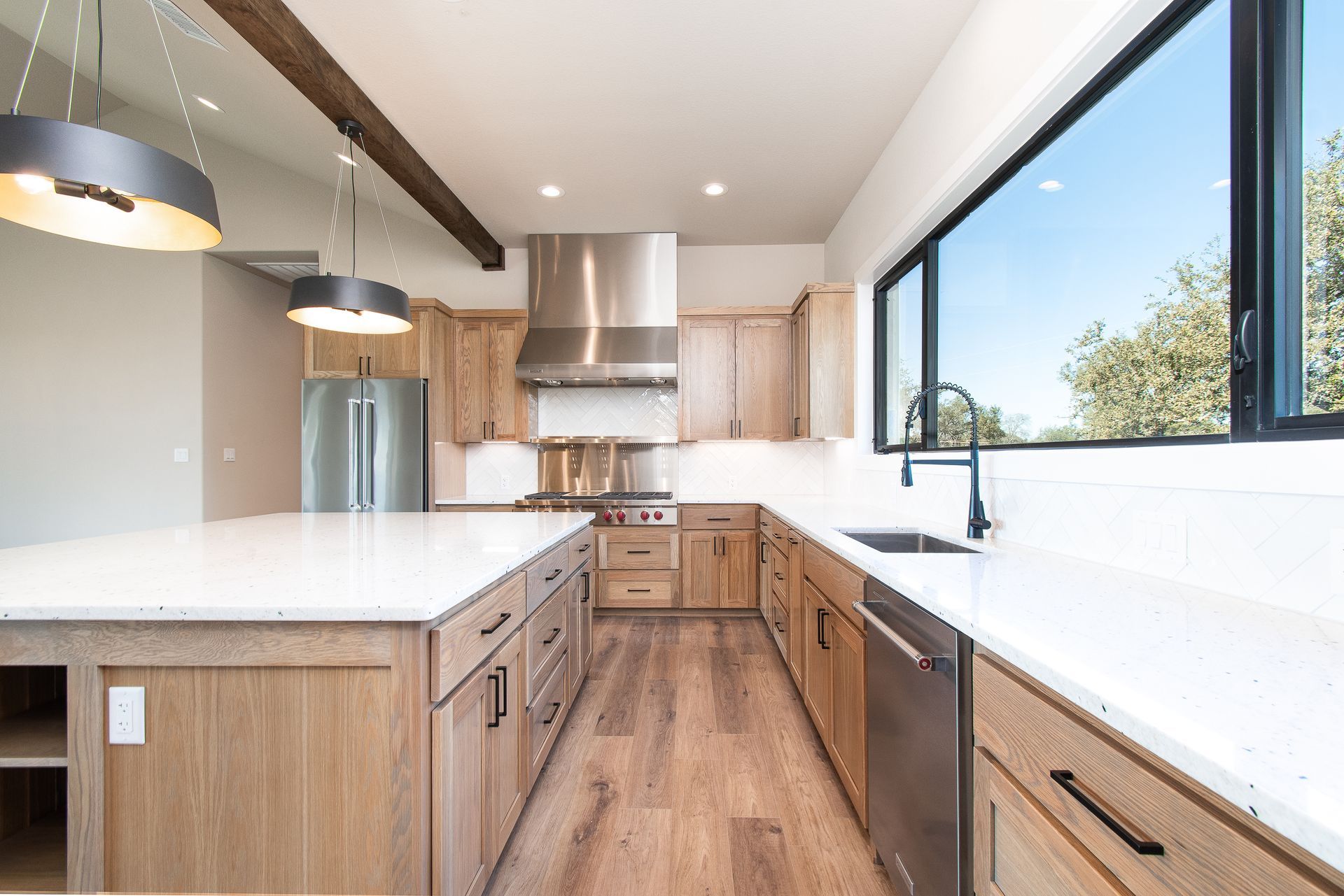 A kitchen with wooden cabinets , white counter tops , stainless steel appliances and a large island.
