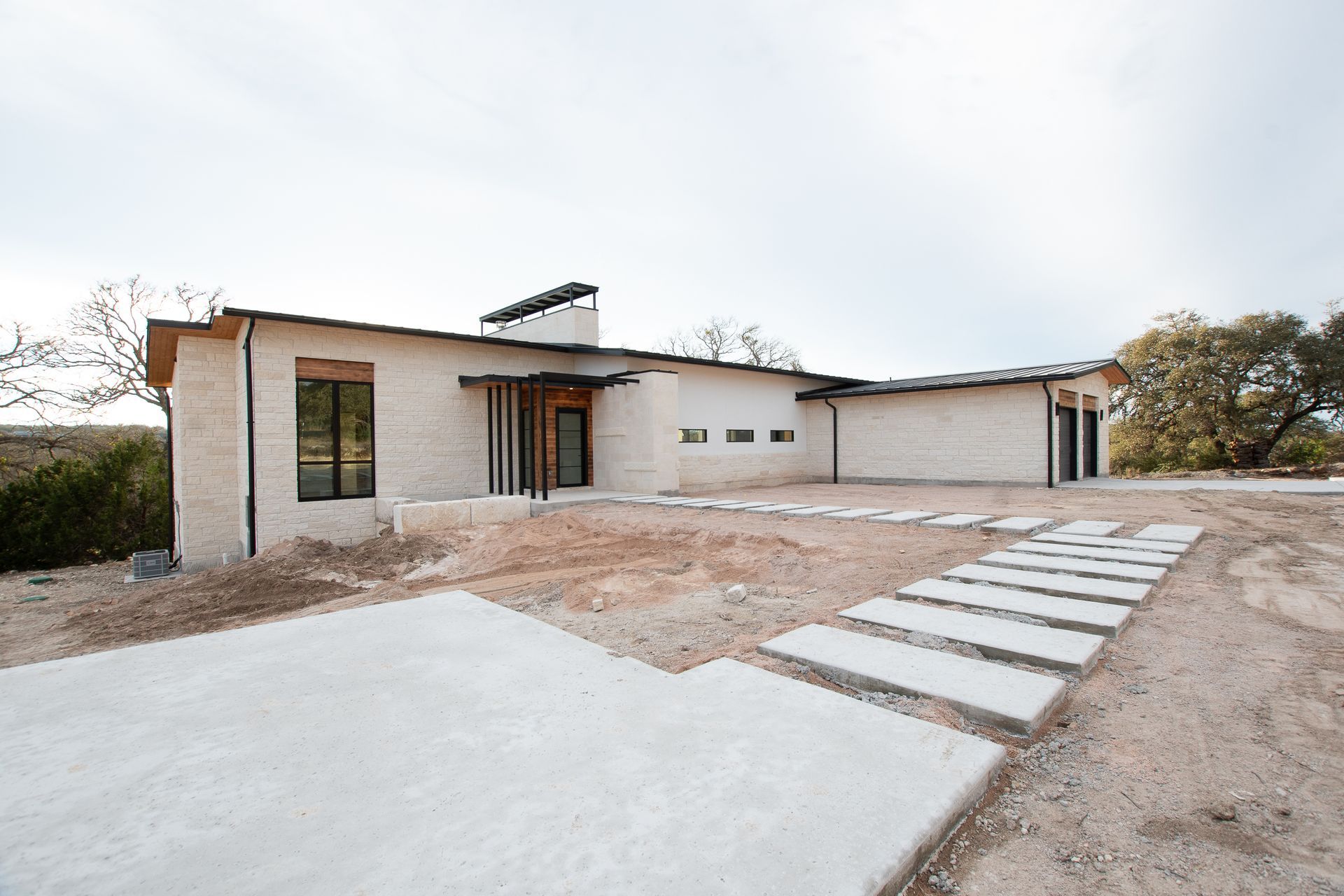 A large white house with a lot of windows is sitting on top of a dirt field.