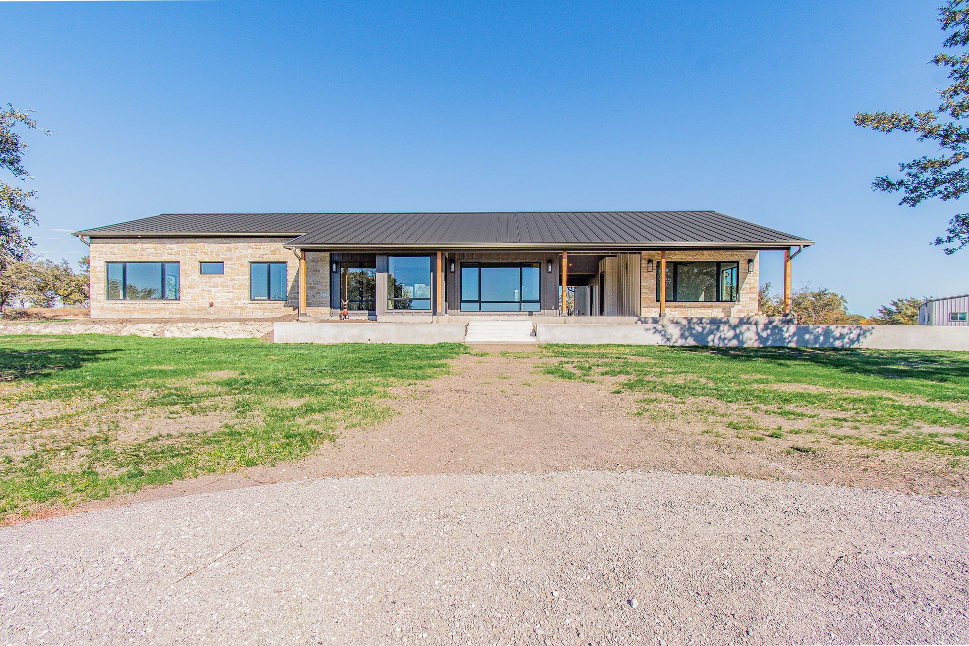 A large house with a lot of windows is sitting on top of a lush green field.