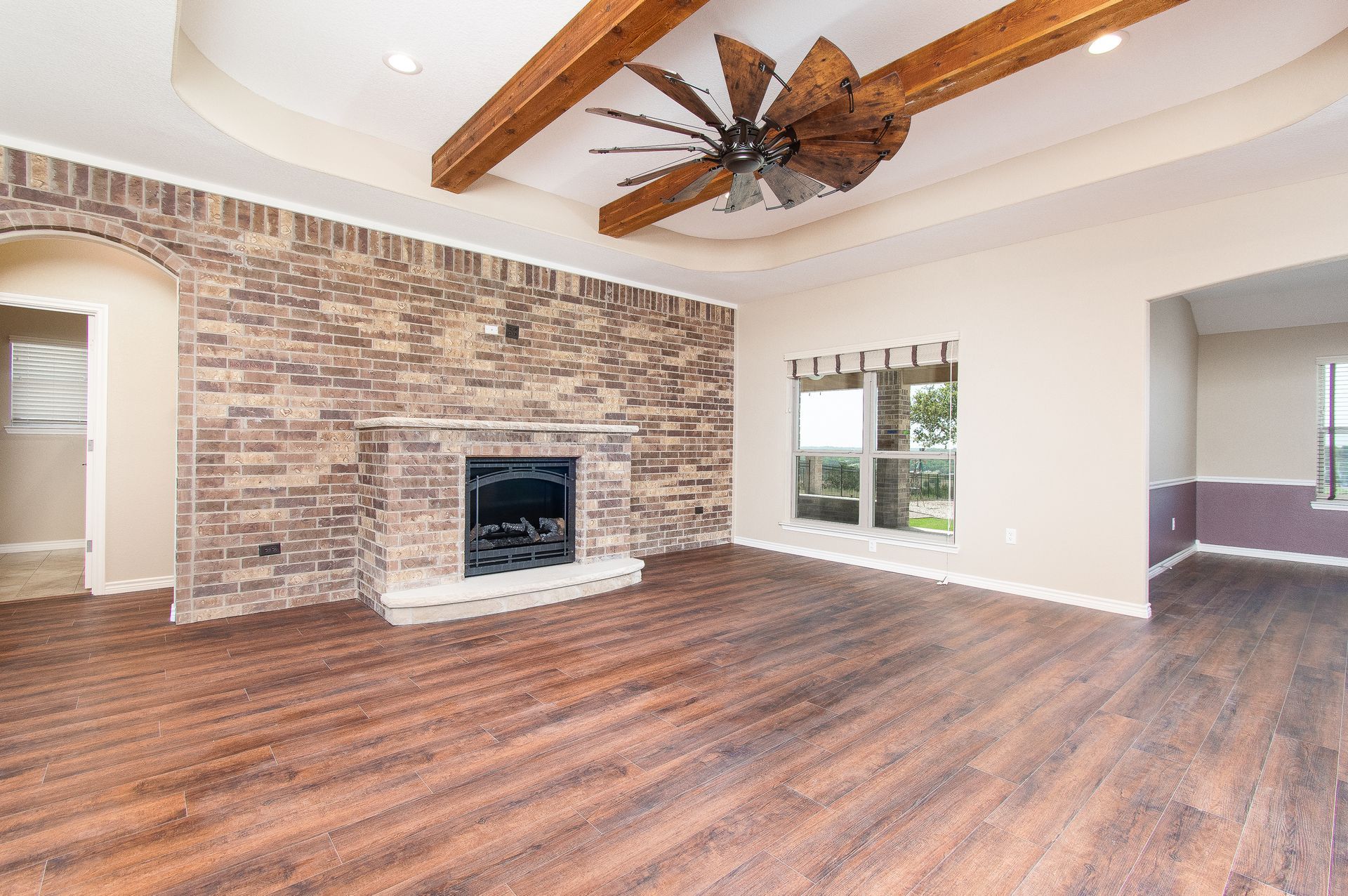 An empty living room with a fireplace and a ceiling fan.