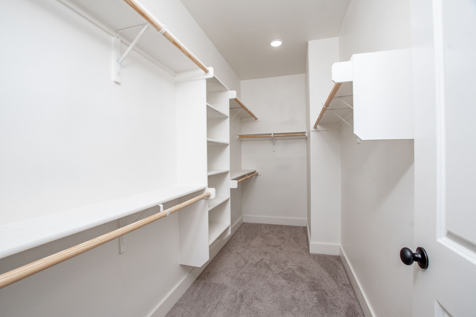 An empty walk in closet with shelves and a door.