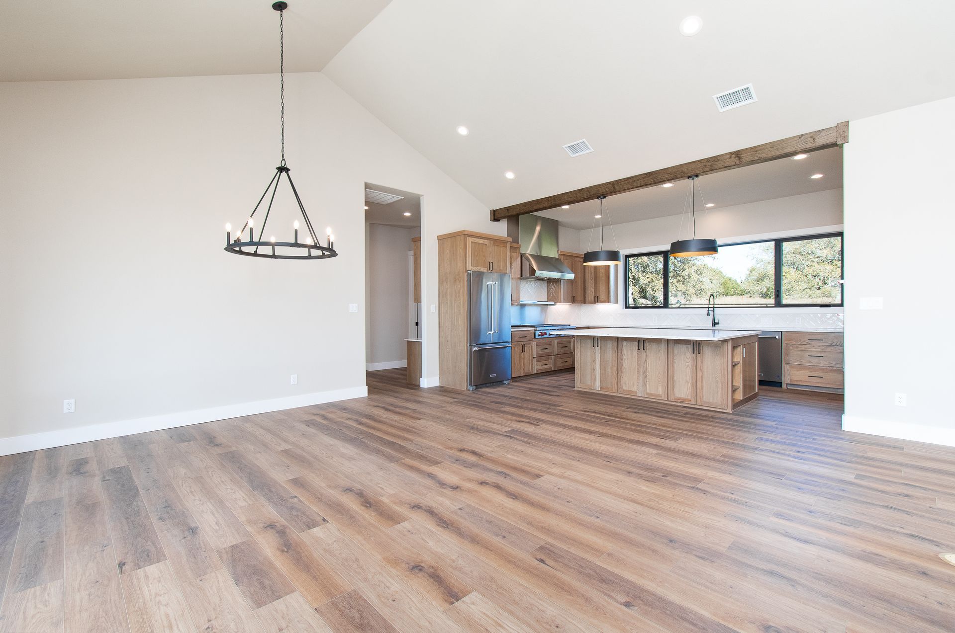 A living room with hardwood floors and a kitchen in the background.
