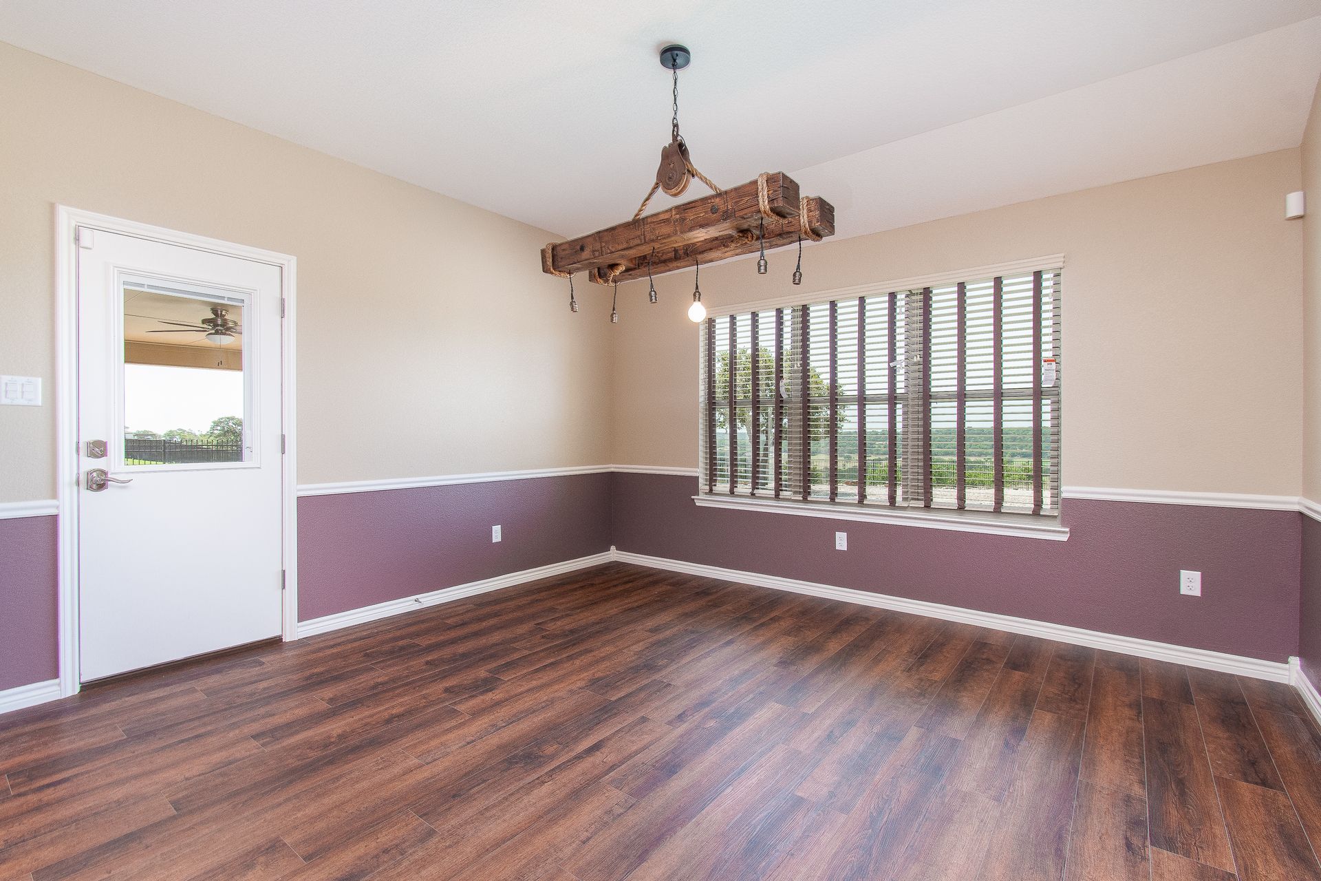An empty living room with hardwood floors and a window.