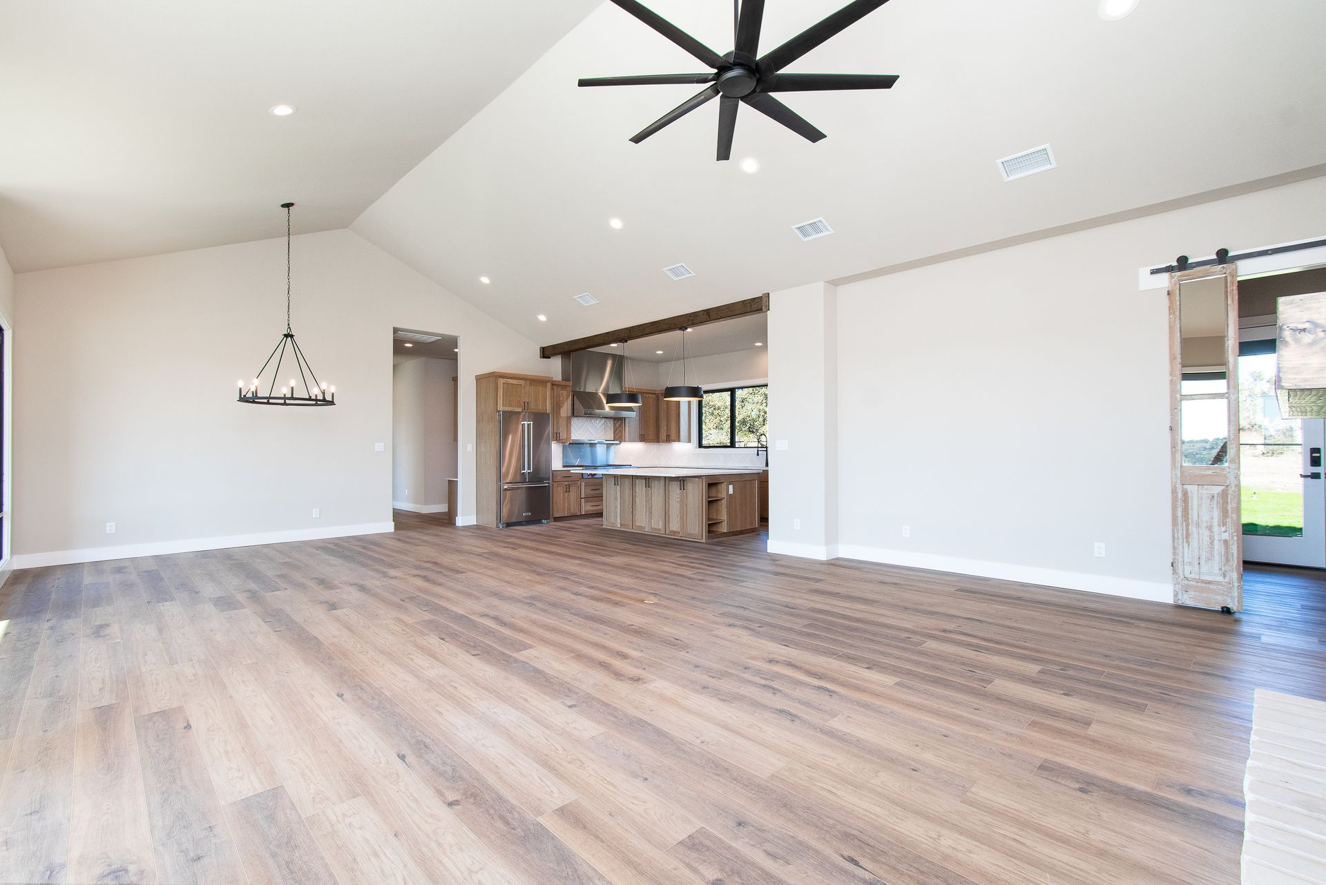 A large empty room with hardwood floors and a ceiling fan.
