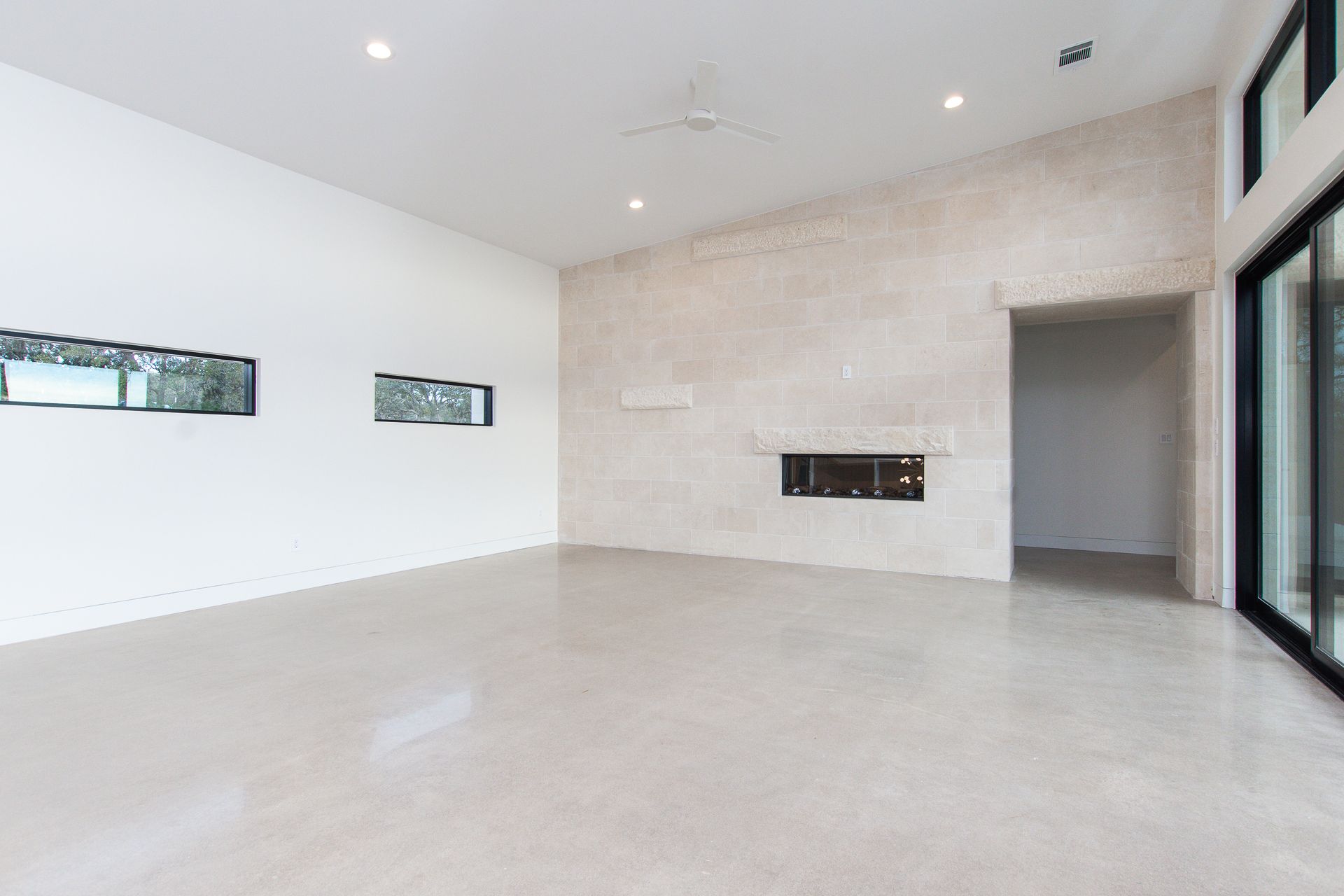 An empty living room with a fireplace and sliding glass doors.