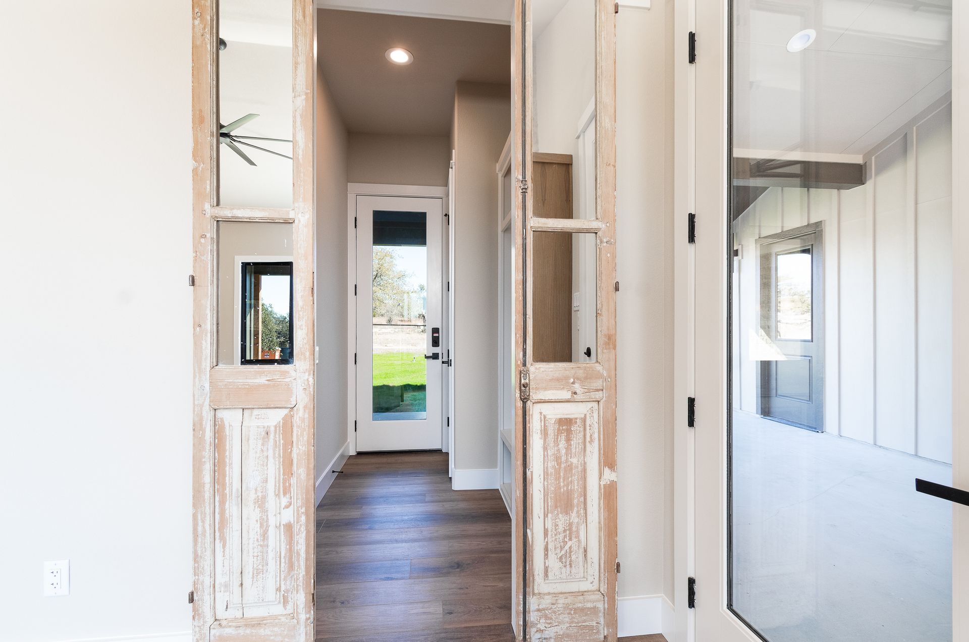 A hallway in a house with a white door and wooden floors.