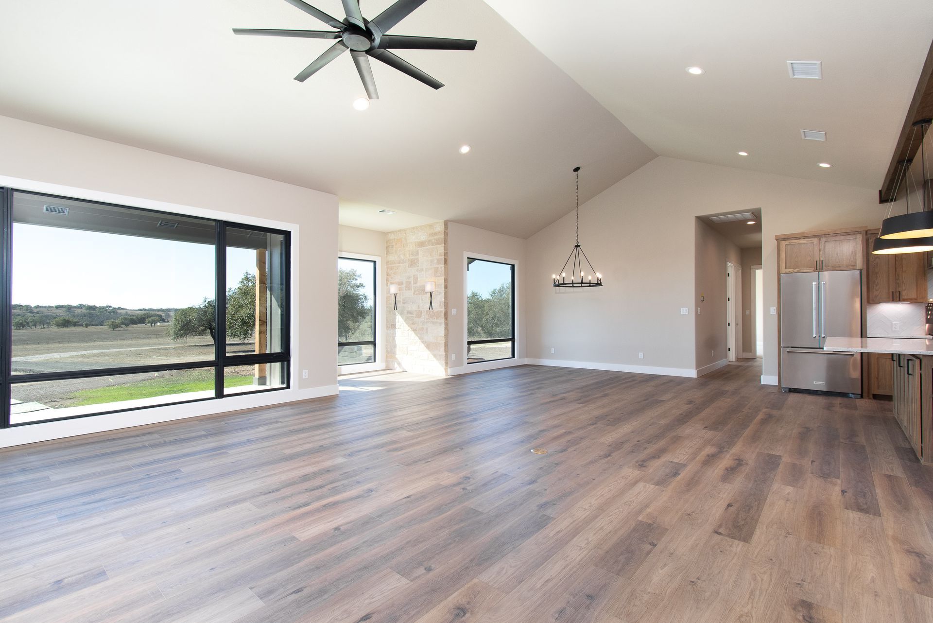 An empty living room with hardwood floors and a ceiling fan