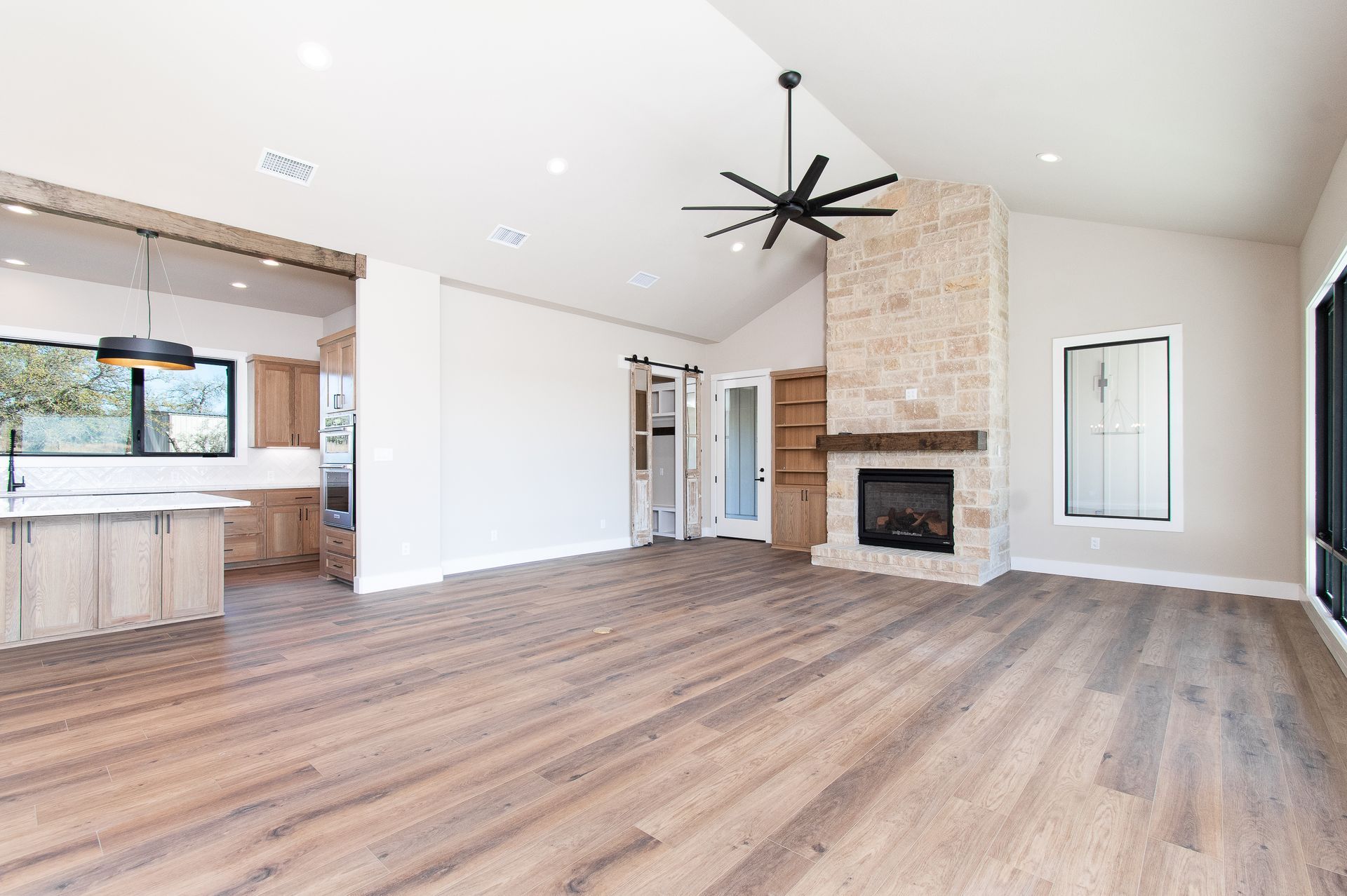 A living room with hardwood floors , a fireplace and a ceiling fan.