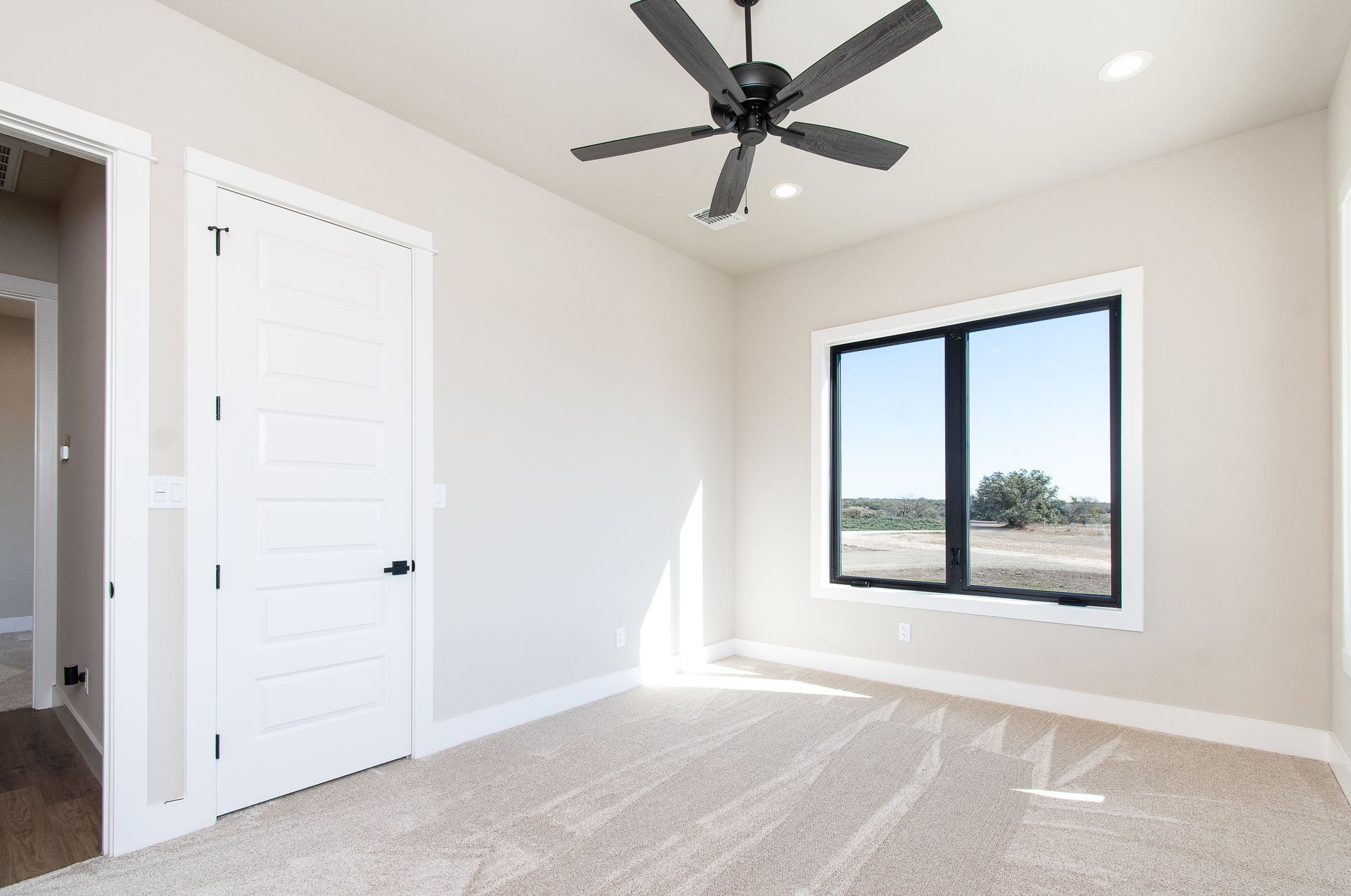 An empty bedroom with a ceiling fan and a window.