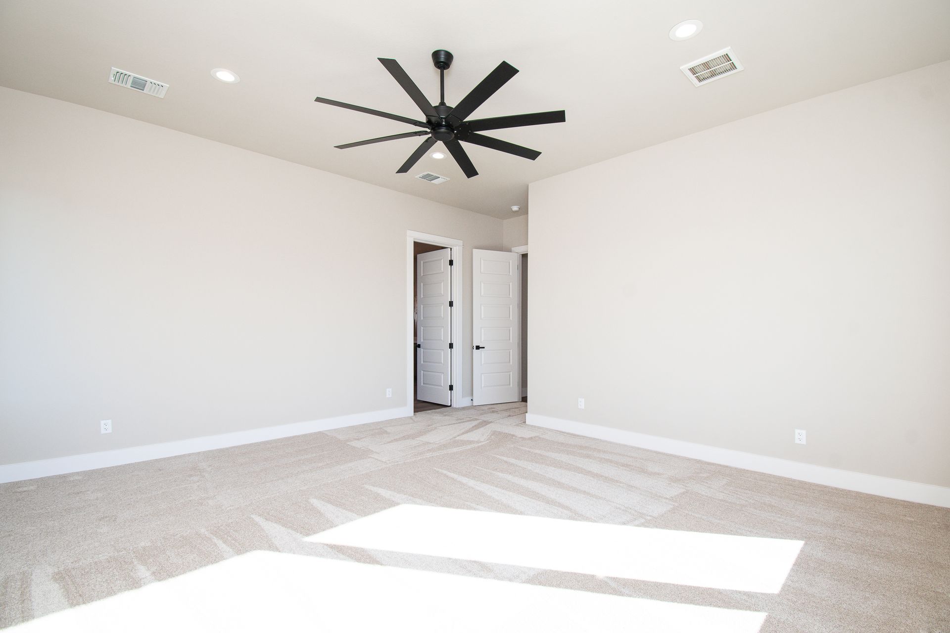 An empty bedroom with a ceiling fan hanging from the ceiling.