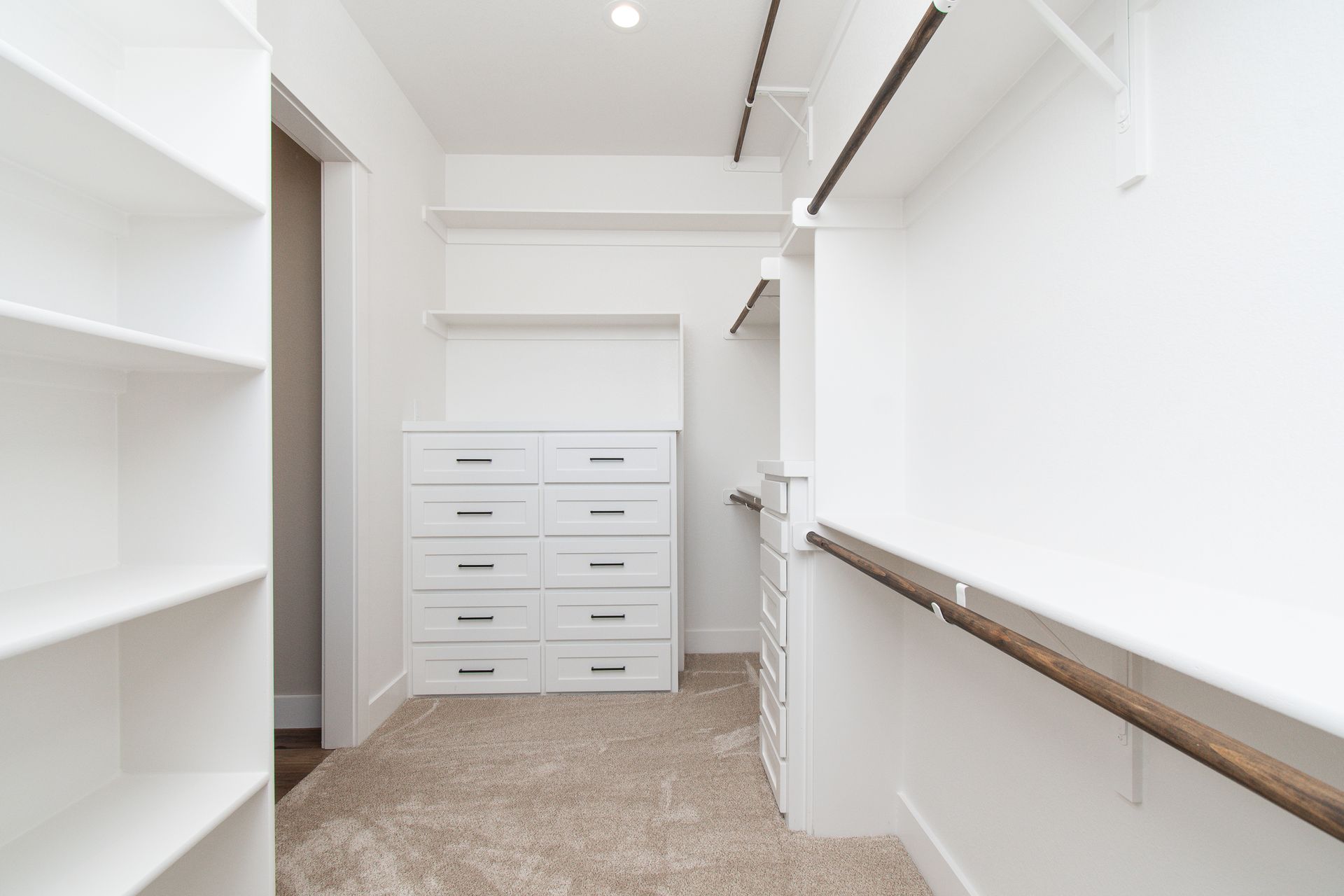 A walk in closet with lots of shelves and drawers