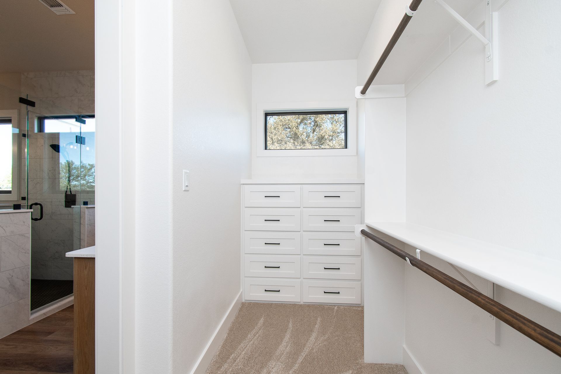 A walk in closet with lots of drawers and a window.
