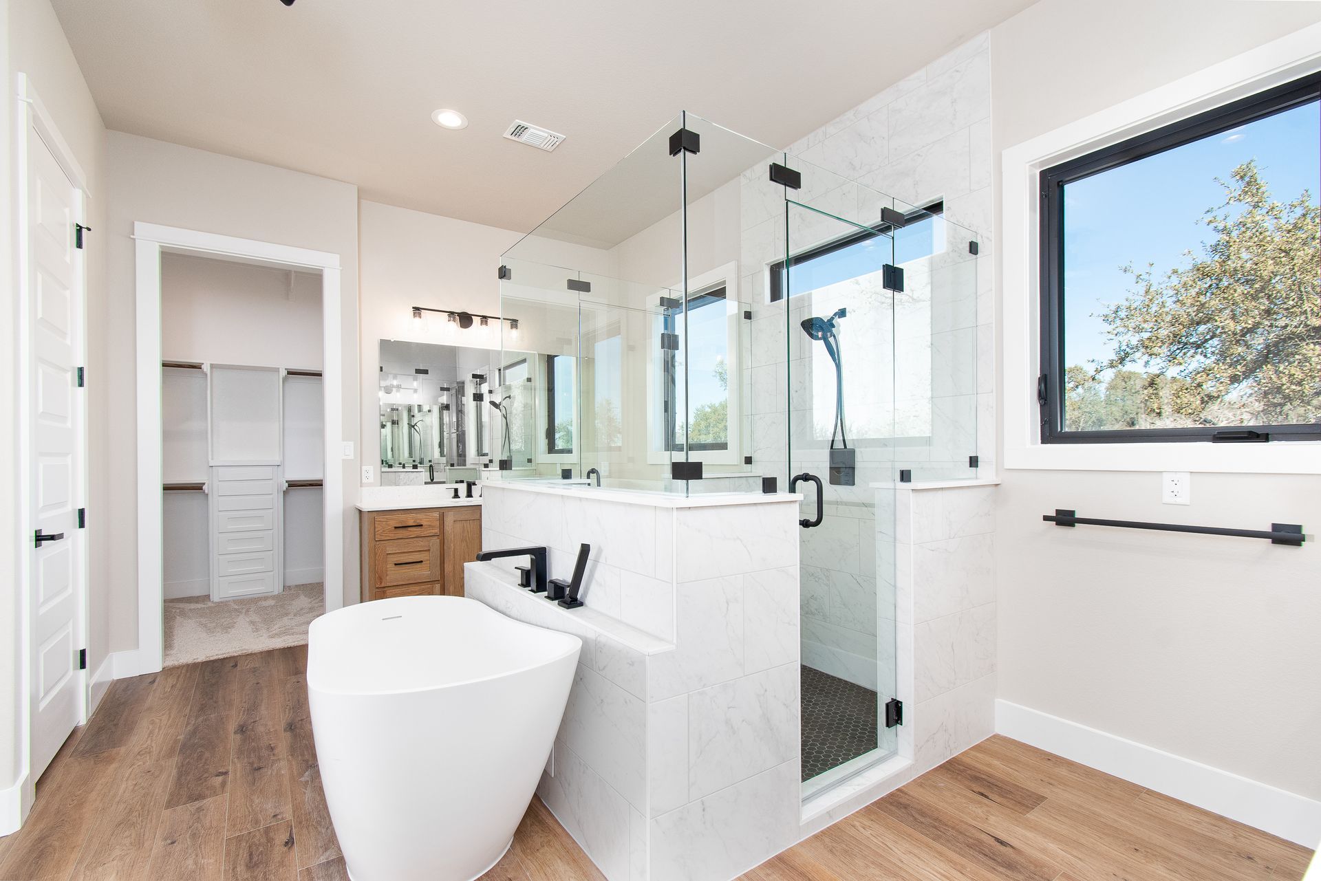 A bathroom with a tub , sink , shower and window.
