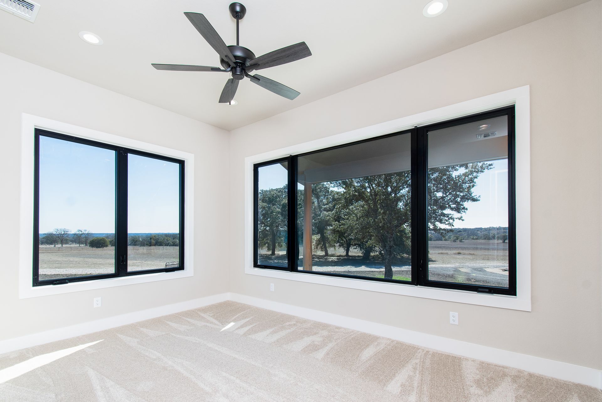 A bedroom with a lot of windows and a ceiling fan.