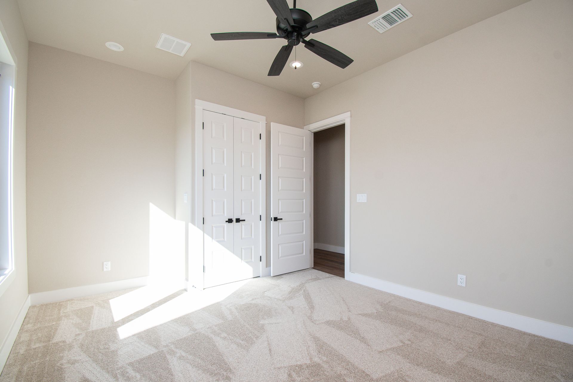An empty bedroom with a ceiling fan and a walk in closet.
