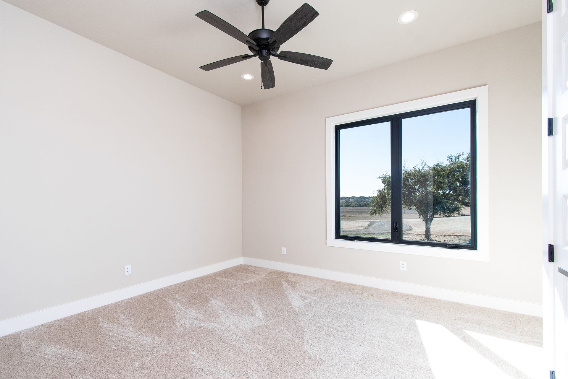 An empty bedroom with a ceiling fan and a window
