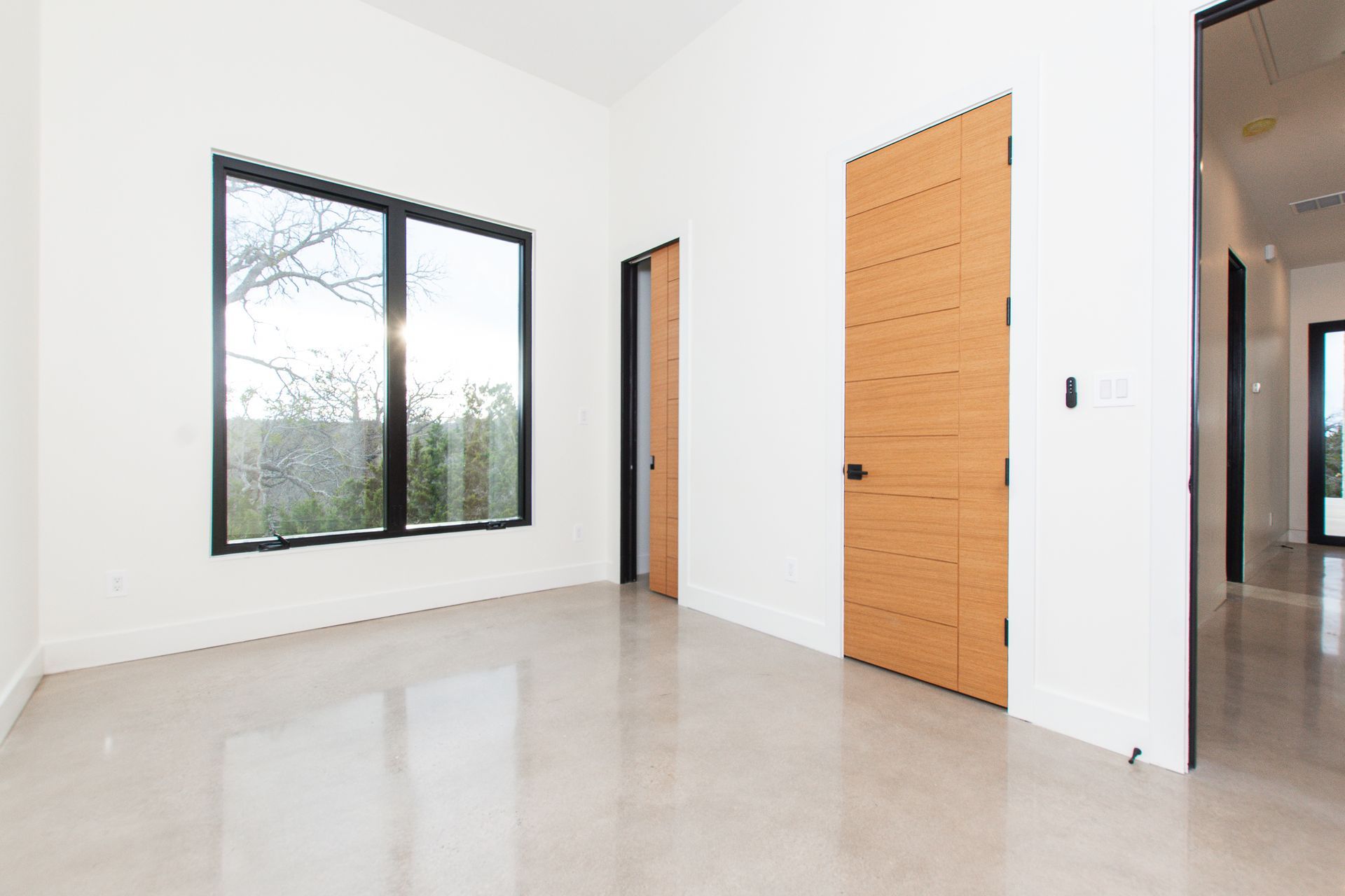 An empty room with two windows and a wooden door