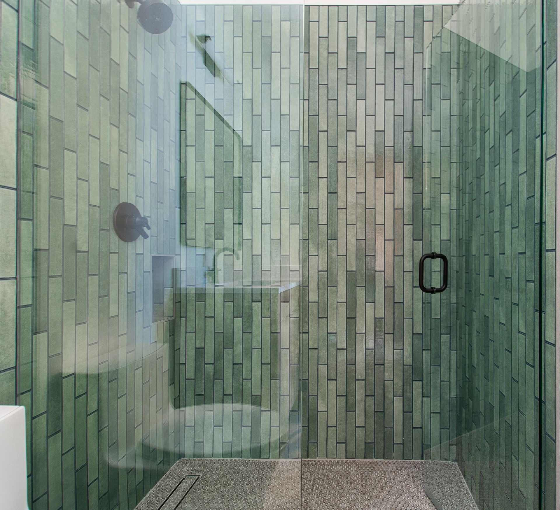 A bathroom with green tiles and a walk in shower.