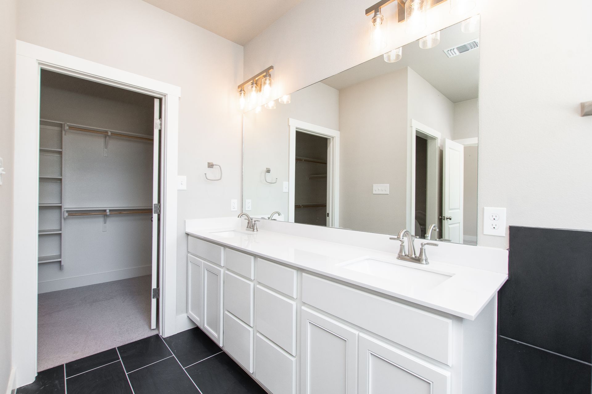 A bathroom with two sinks and a walk in closet.