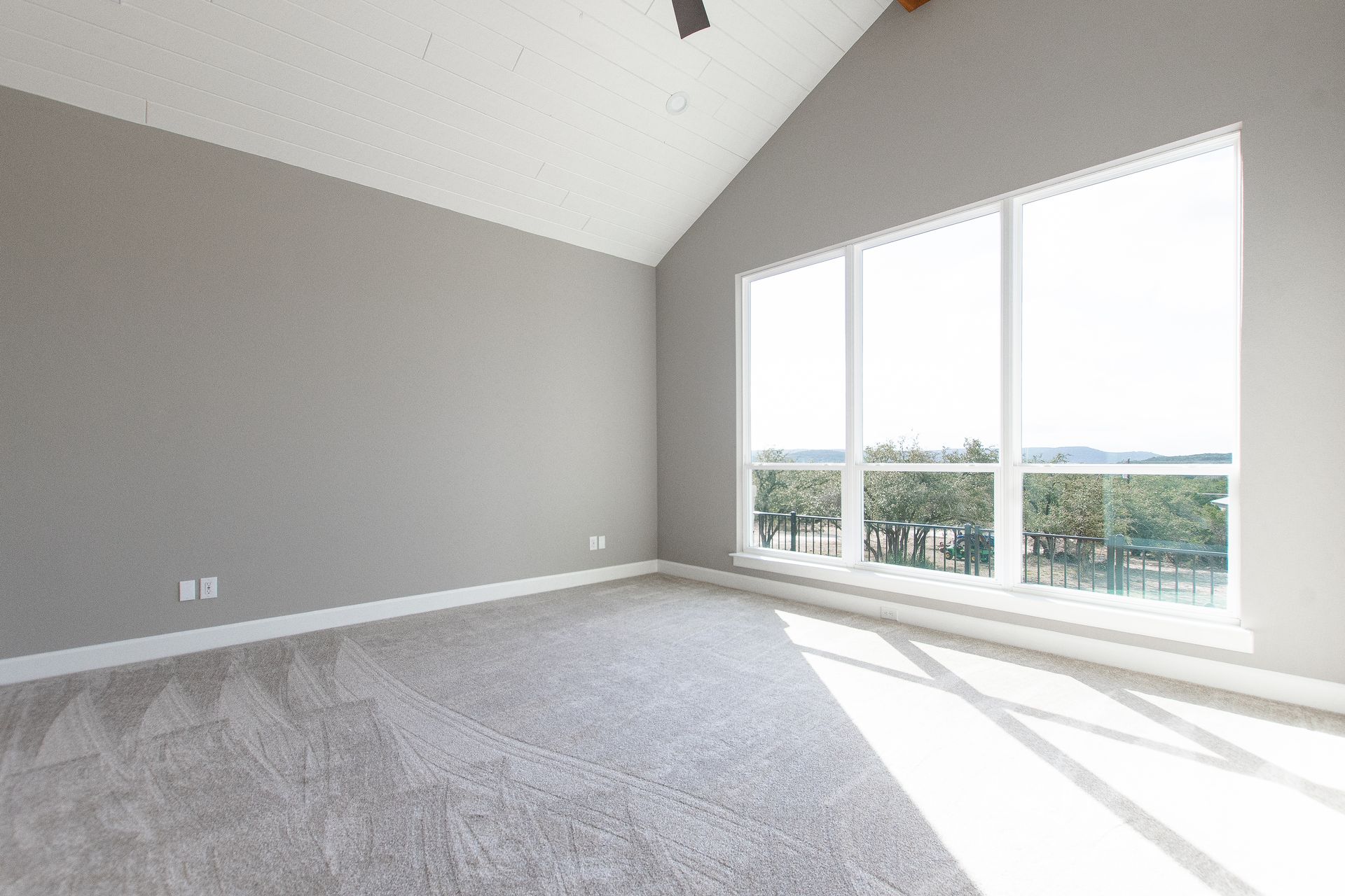 An empty bedroom with a vaulted ceiling and lots of windows.