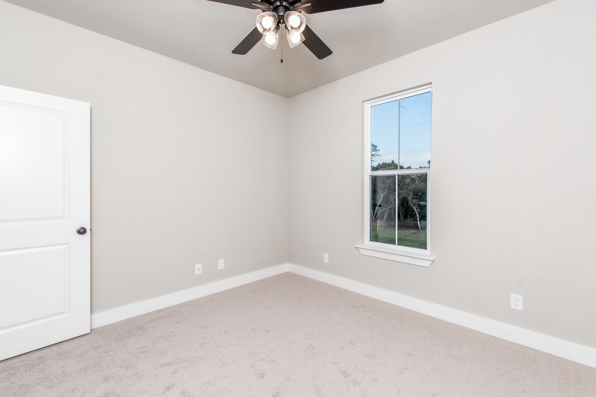 An empty bedroom with a ceiling fan and a window.