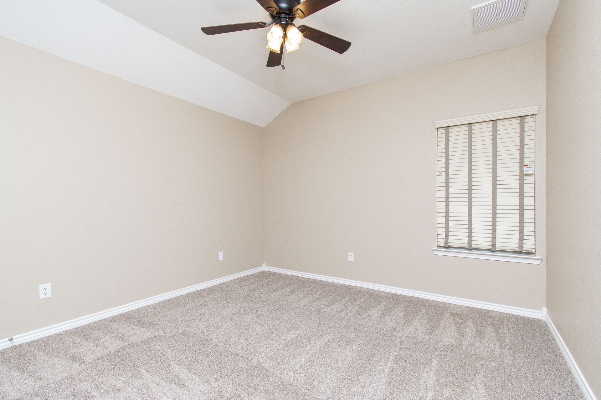 An empty bedroom with a ceiling fan and a window.