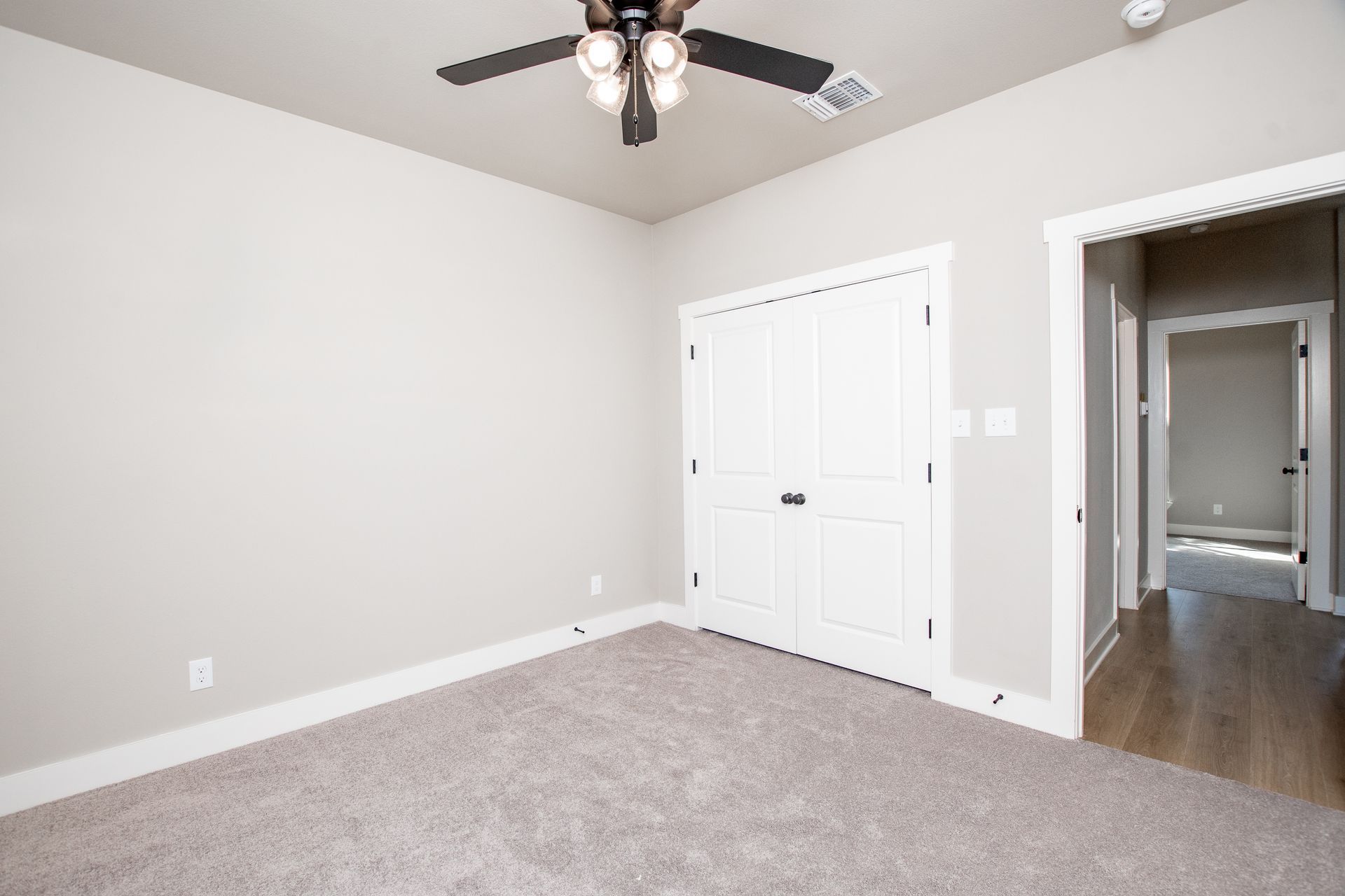An empty bedroom with a ceiling fan and a closet.