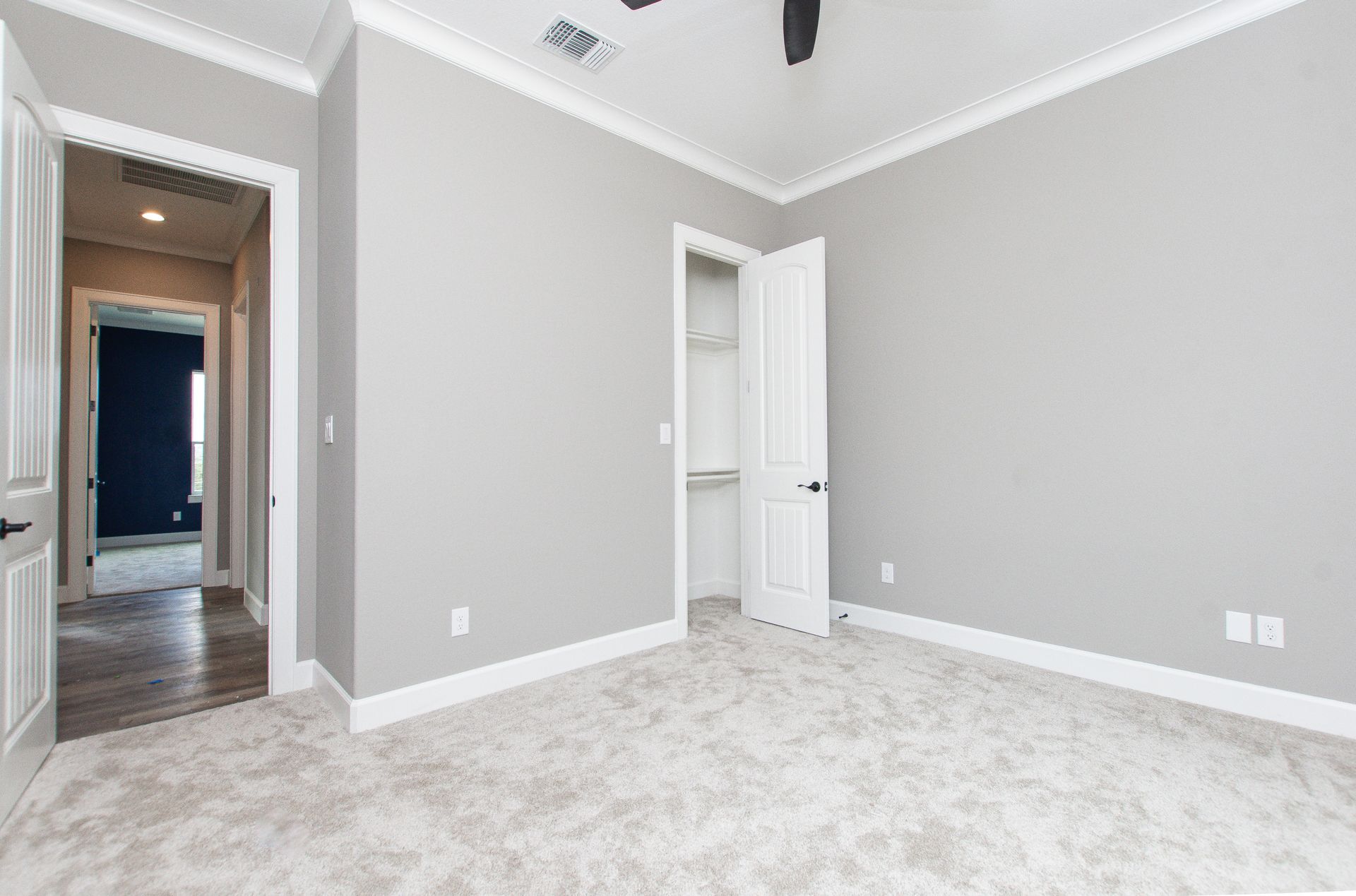 An empty bedroom with a ceiling fan and a walk in closet.
